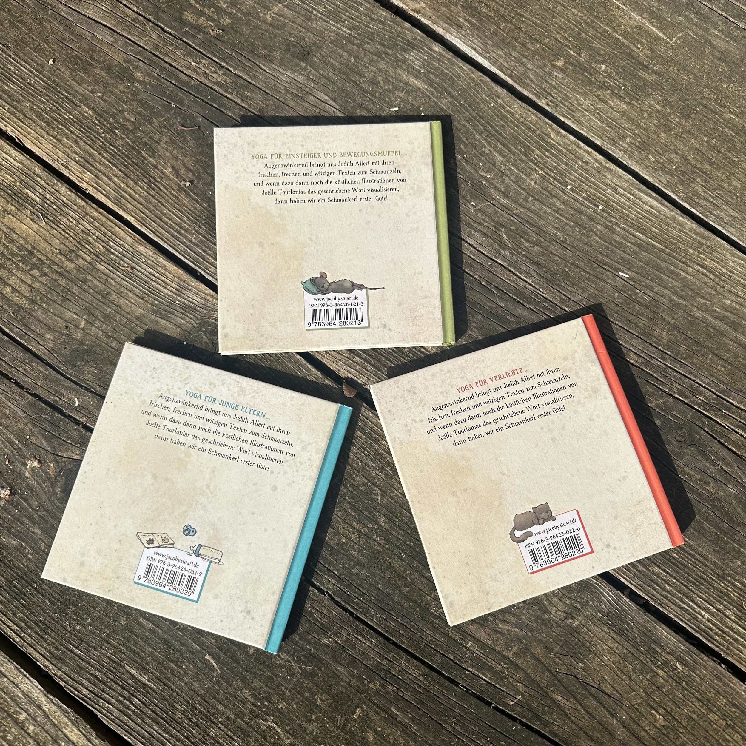 Ein Foto der drei Wollschweinyogabücher. Die Rückseite ist zu sehen.