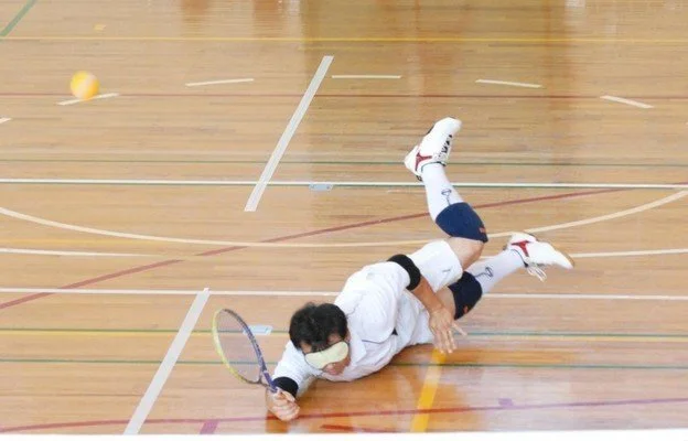 Takei Myoshi duikt naar de bal met een racket in zijn hand.