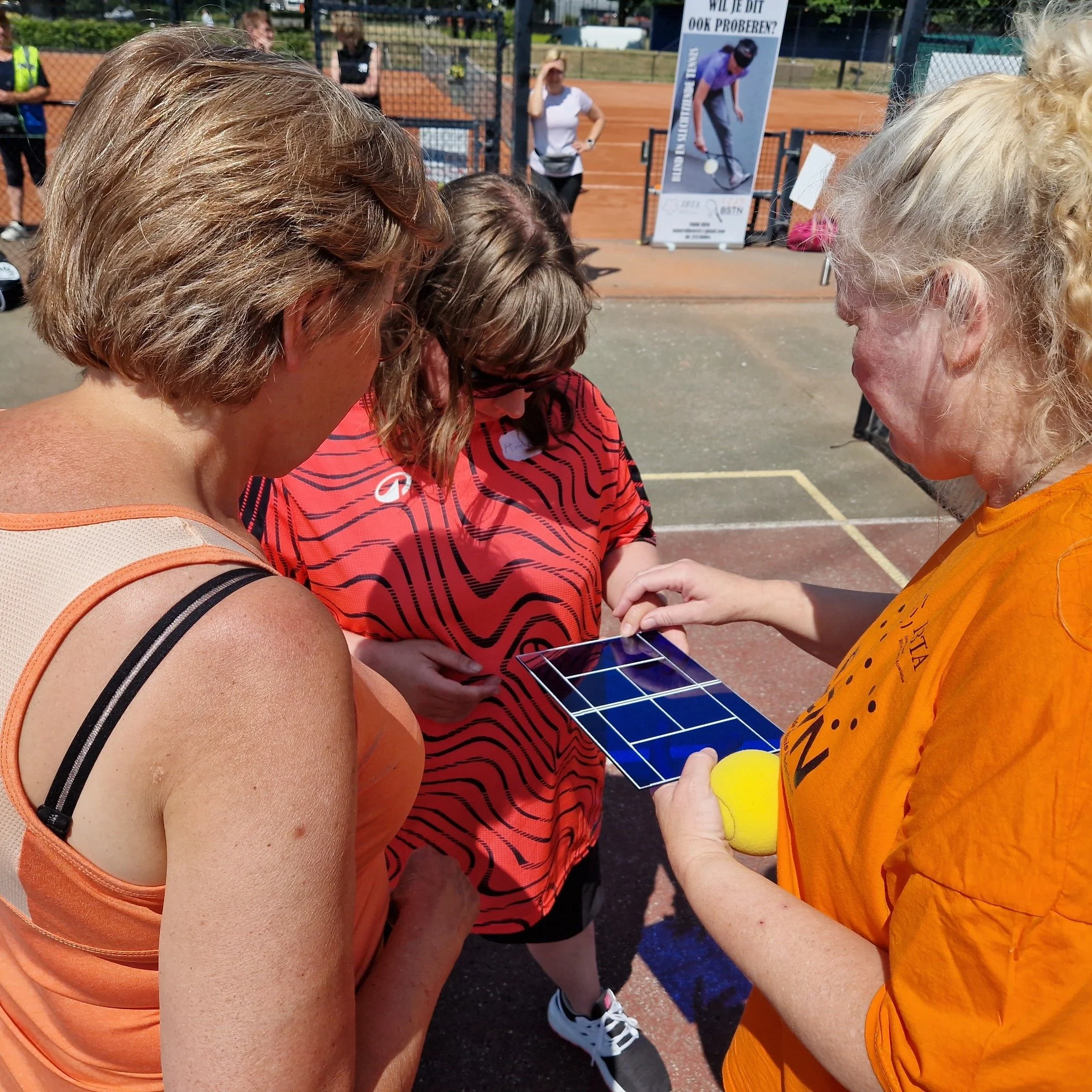 Fanny met een voelbare maquette in haar handen . Ze leidt een slechtziende deelnemer haar handen over de maquette. Een derde mevrouw kijkt toe vanuit het perspectief van de fotograaf.