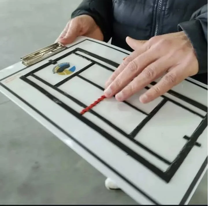 Voelbare maquette van tennisbaan met hand die het net voelt. 