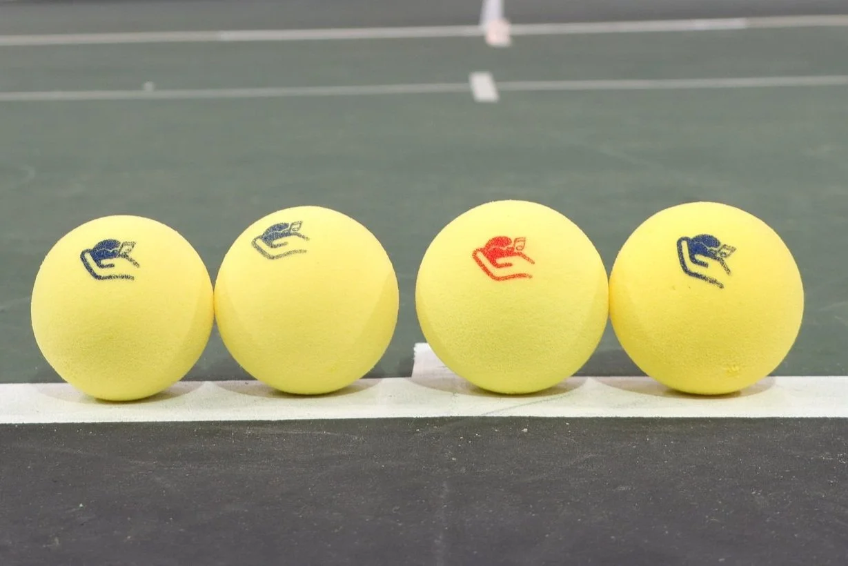 Vier auditieve tennisballen netjes op een rij. 