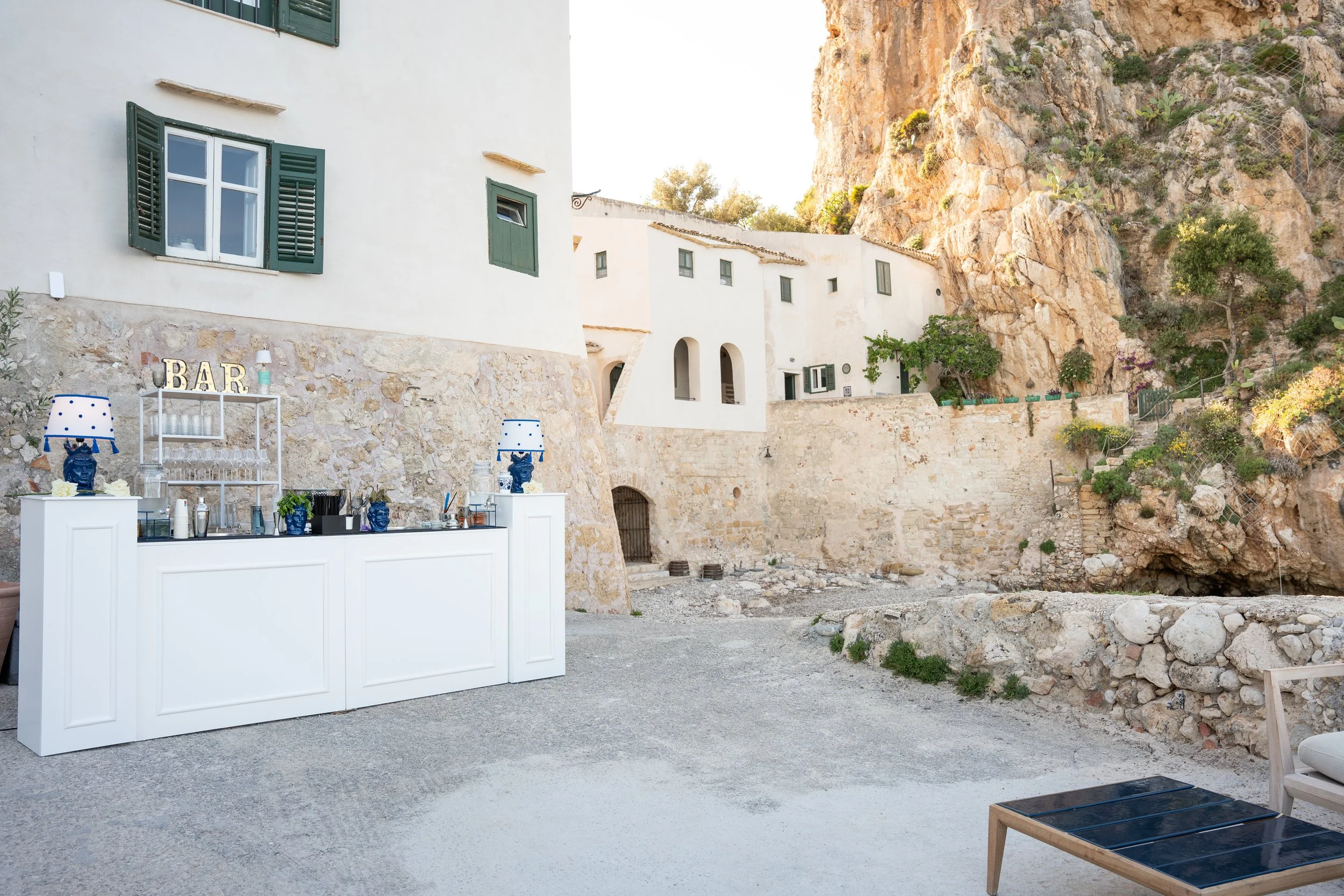 Bar a bordo piscina con decorazioni blu, sfondo di case bianche e scogliere.