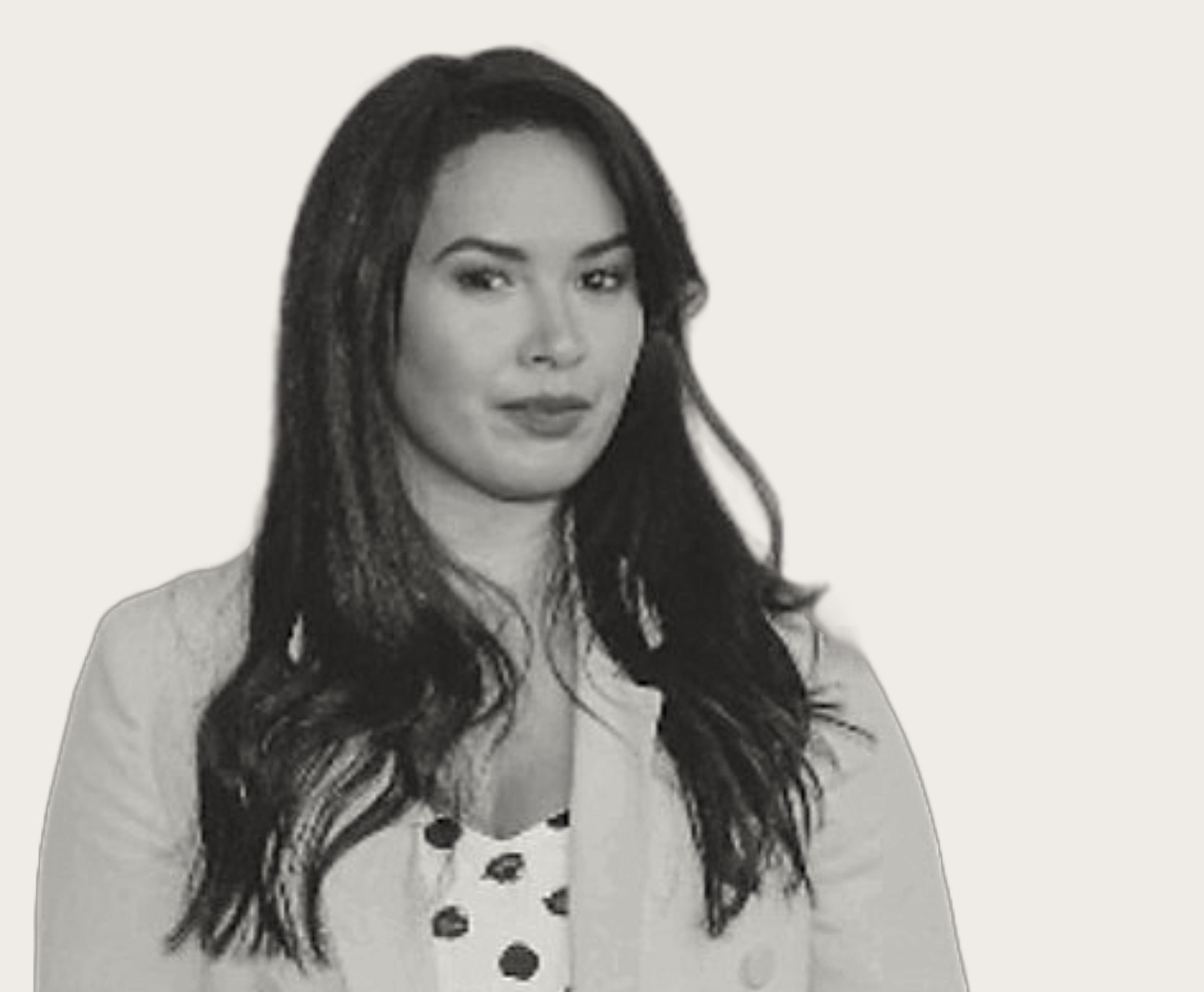Black and white photo of a woman with long hair wearing a light-colored jacket and polka dot blouse.