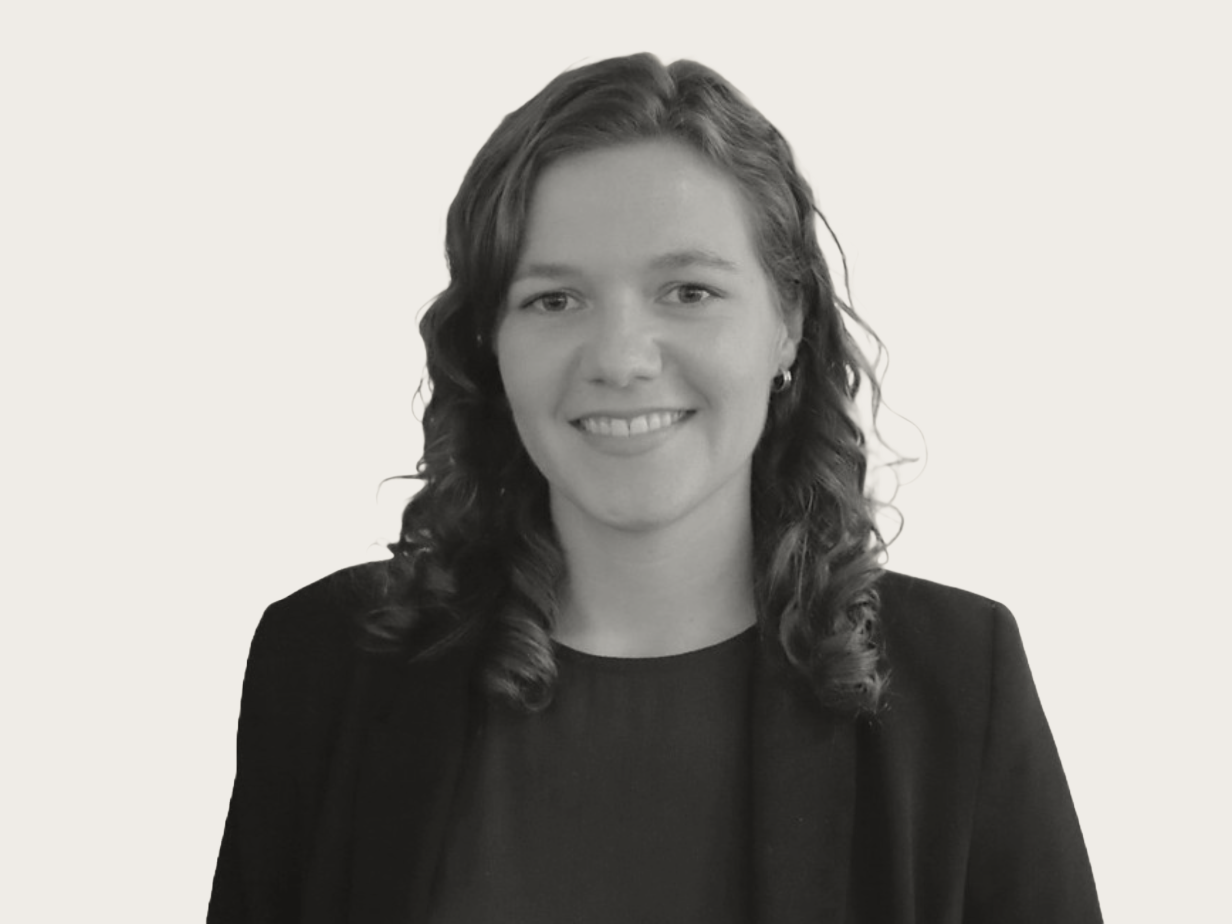 Black and white portrait of a woman with curly hair, wearing a blazer, smiling.