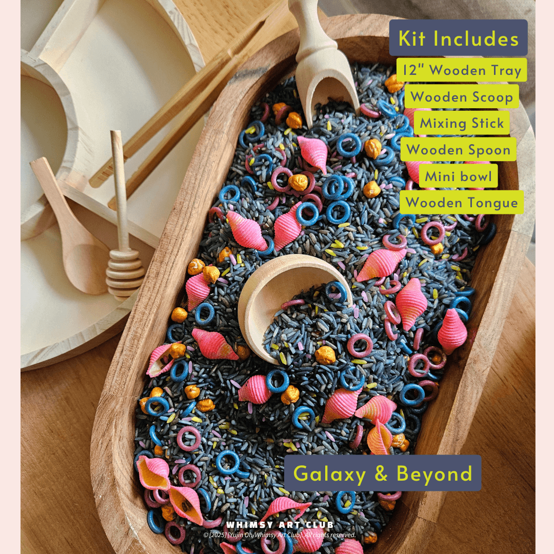 Galaxy & Beyond sensory play kit displaying a wooden tray filled with dark blue and black rice mixed with pink shell-shaped objects, blue rings, and golden beads.