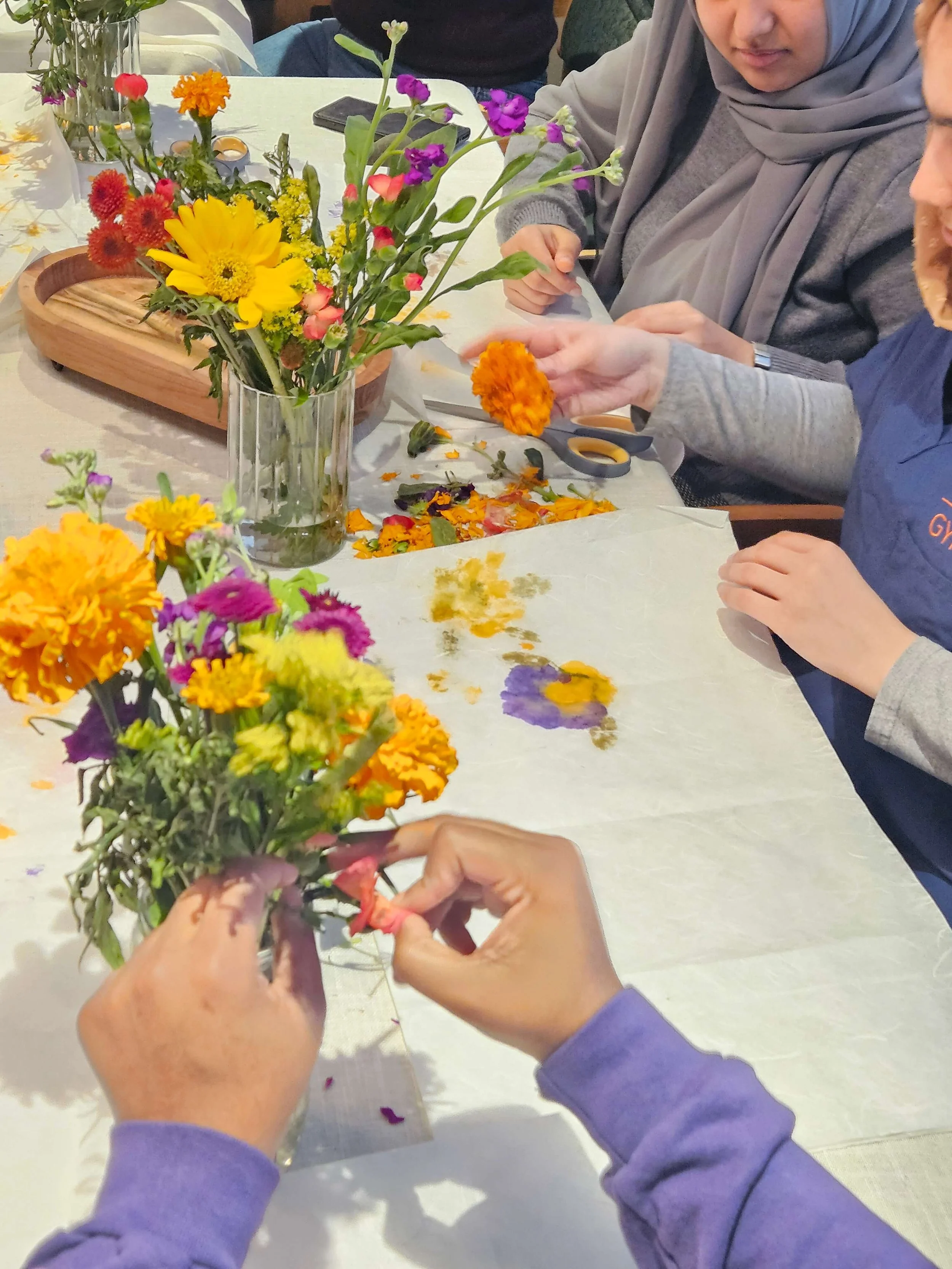 People making flower arrangements with colorful flowers on a table.