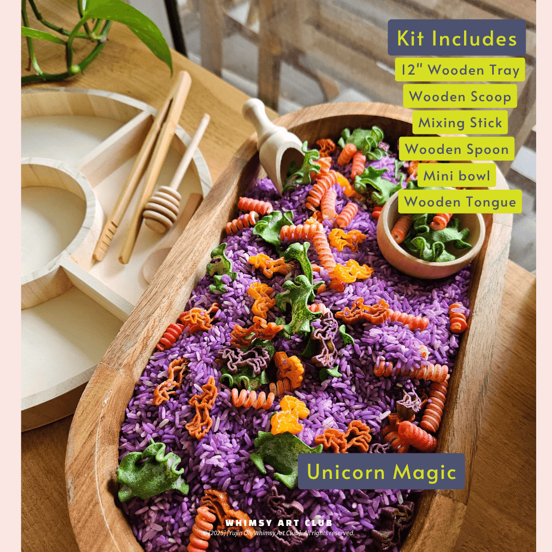 Unicorn Magic sensory play kit featuring a wooden tray filled with purple rice, orange spiral pasta, and green leafy decorations.