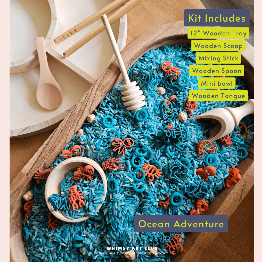 Blue rice and sea animal-shaped pasta in a wooden tray with scoops, tongs, and a mixing stick;