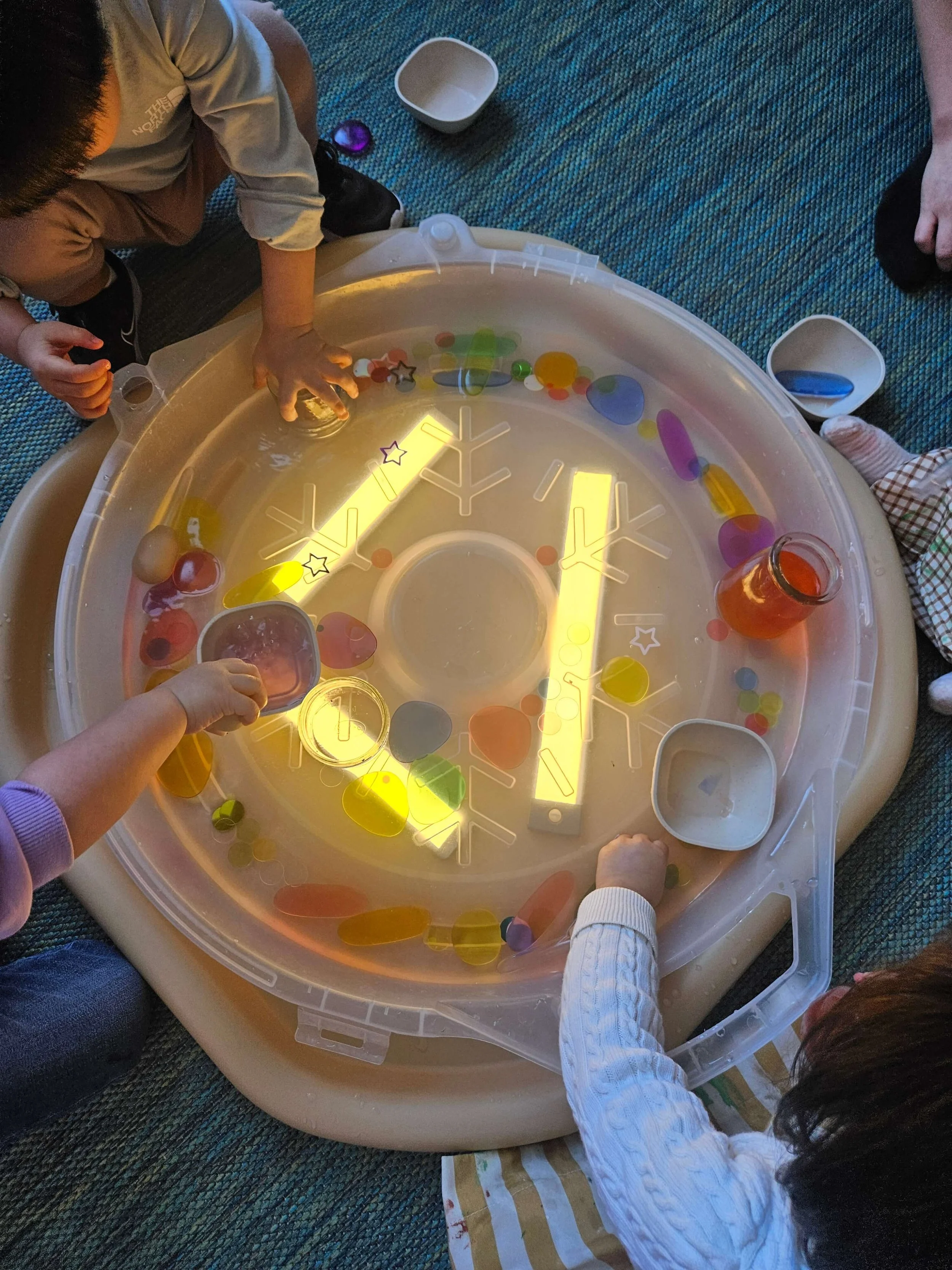 Toddlers exploring light, color, and water during a sensory play activity at Whimsy Art Club toddler art class in Fort Lee, New Jersey.