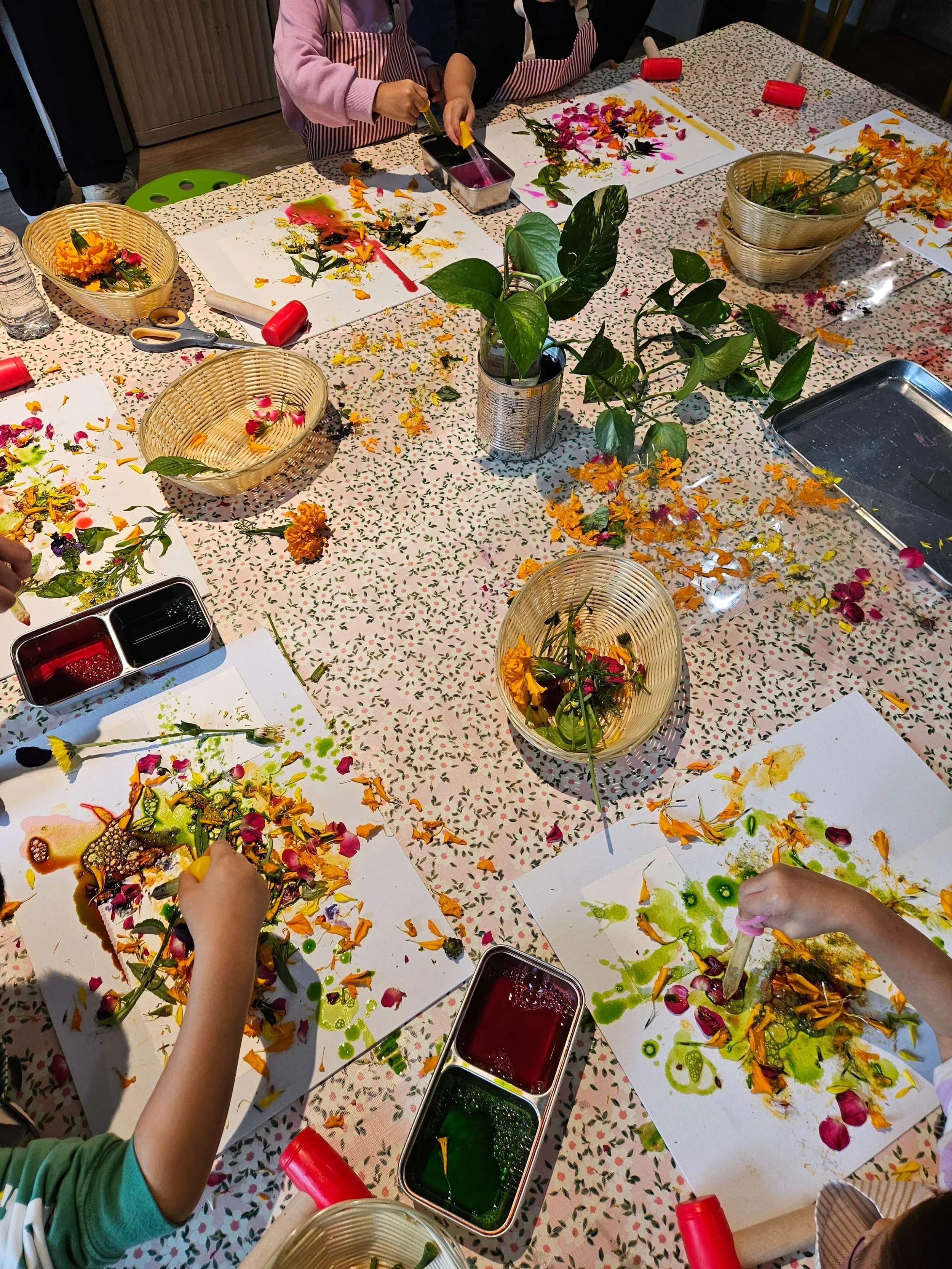 Children explore petals, paint, and natural textures while making their own artwork at a Whimsy Art Club birthday party.