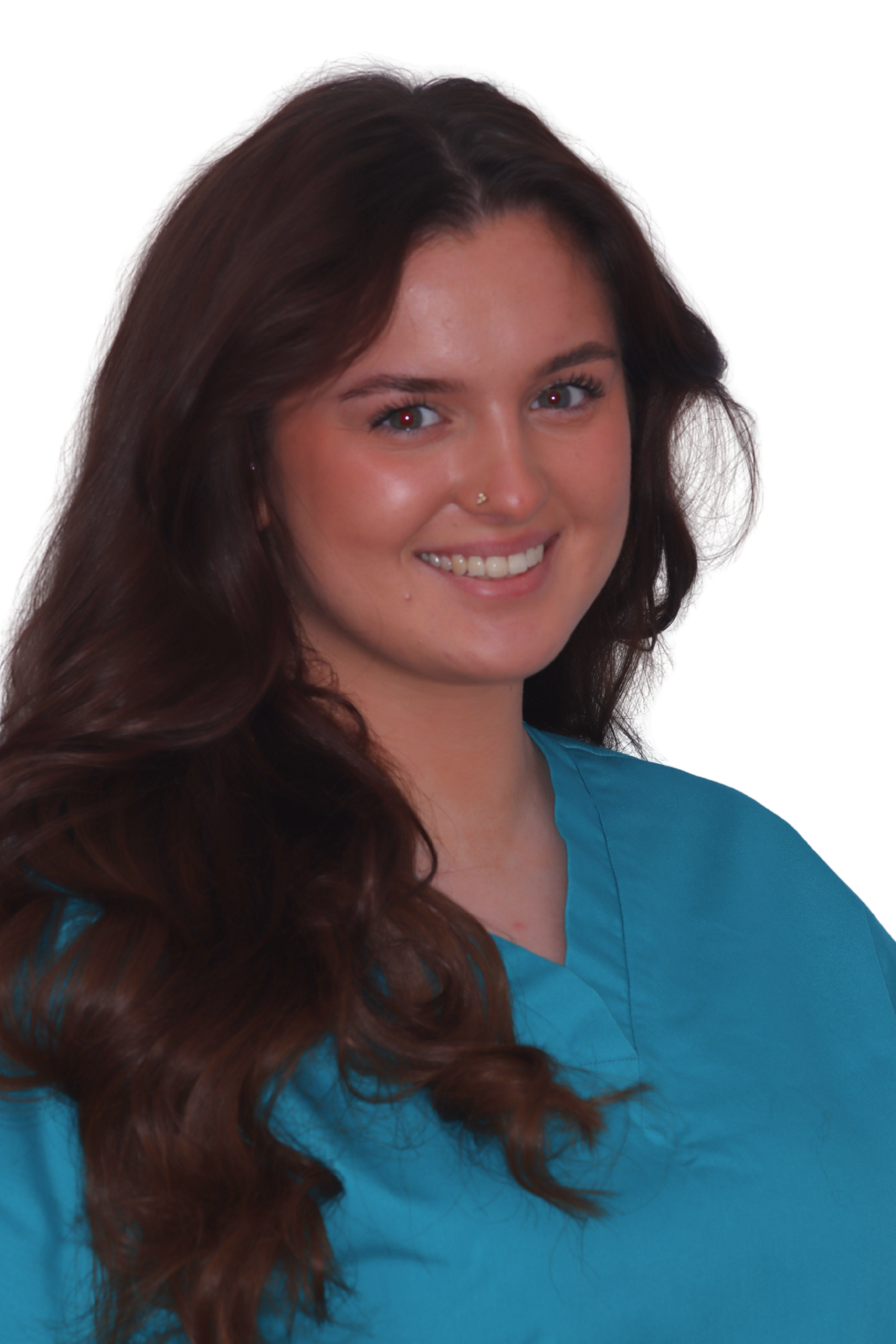Smiling woman wearing blue scrubs with hair tied back, standing against a plain white background.