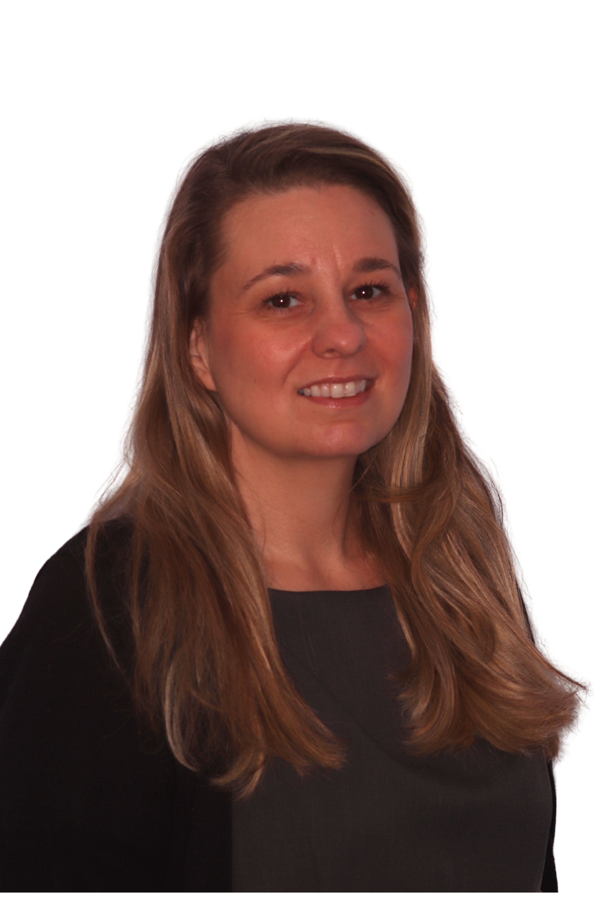 Person smiling in a dark turtleneck with long brown hair against a plain background.