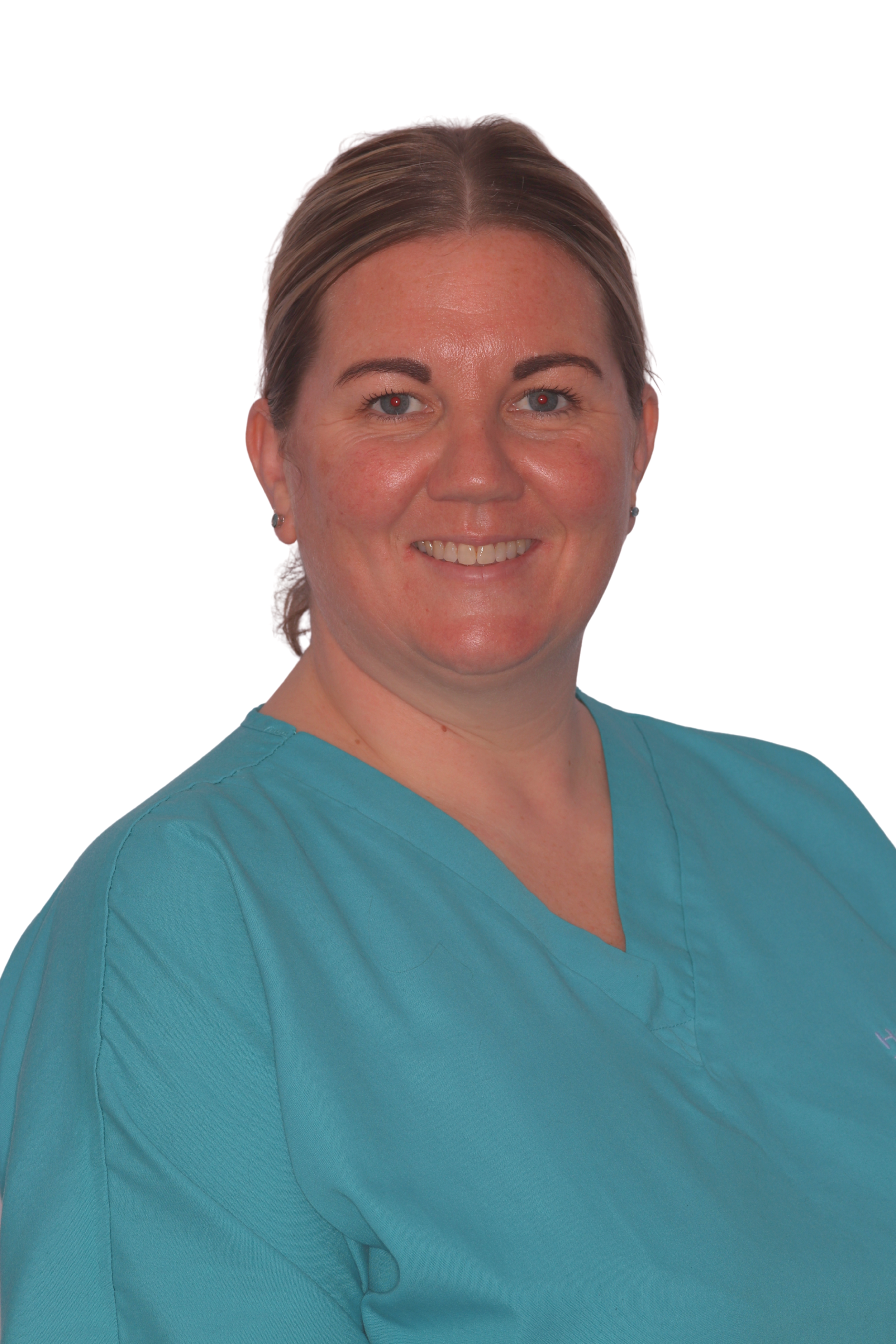 A woman wearing a blue medical scrub top smiling against a plain background.