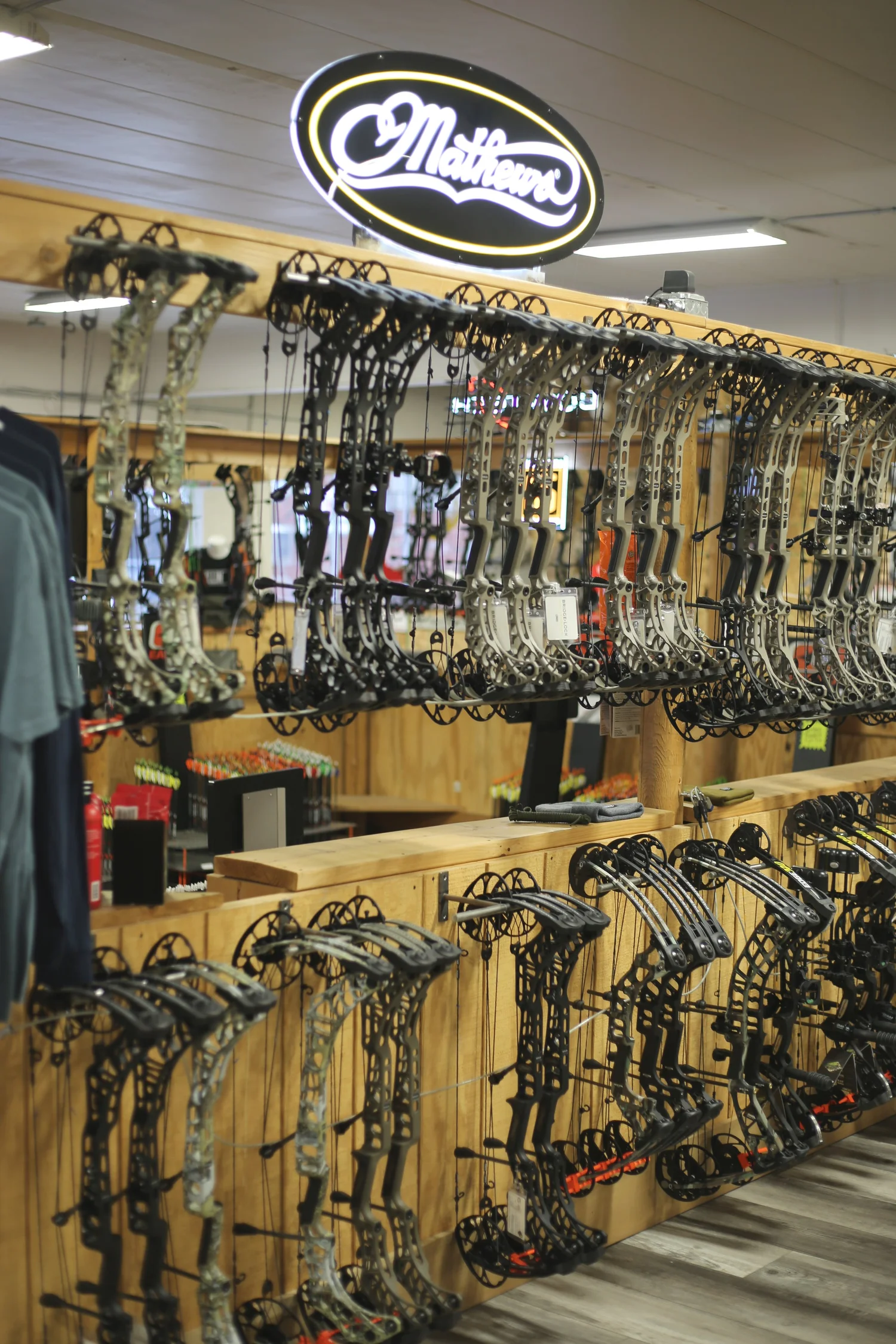Wall of Mathews compound bows under a lighted Mathews sign in the shop