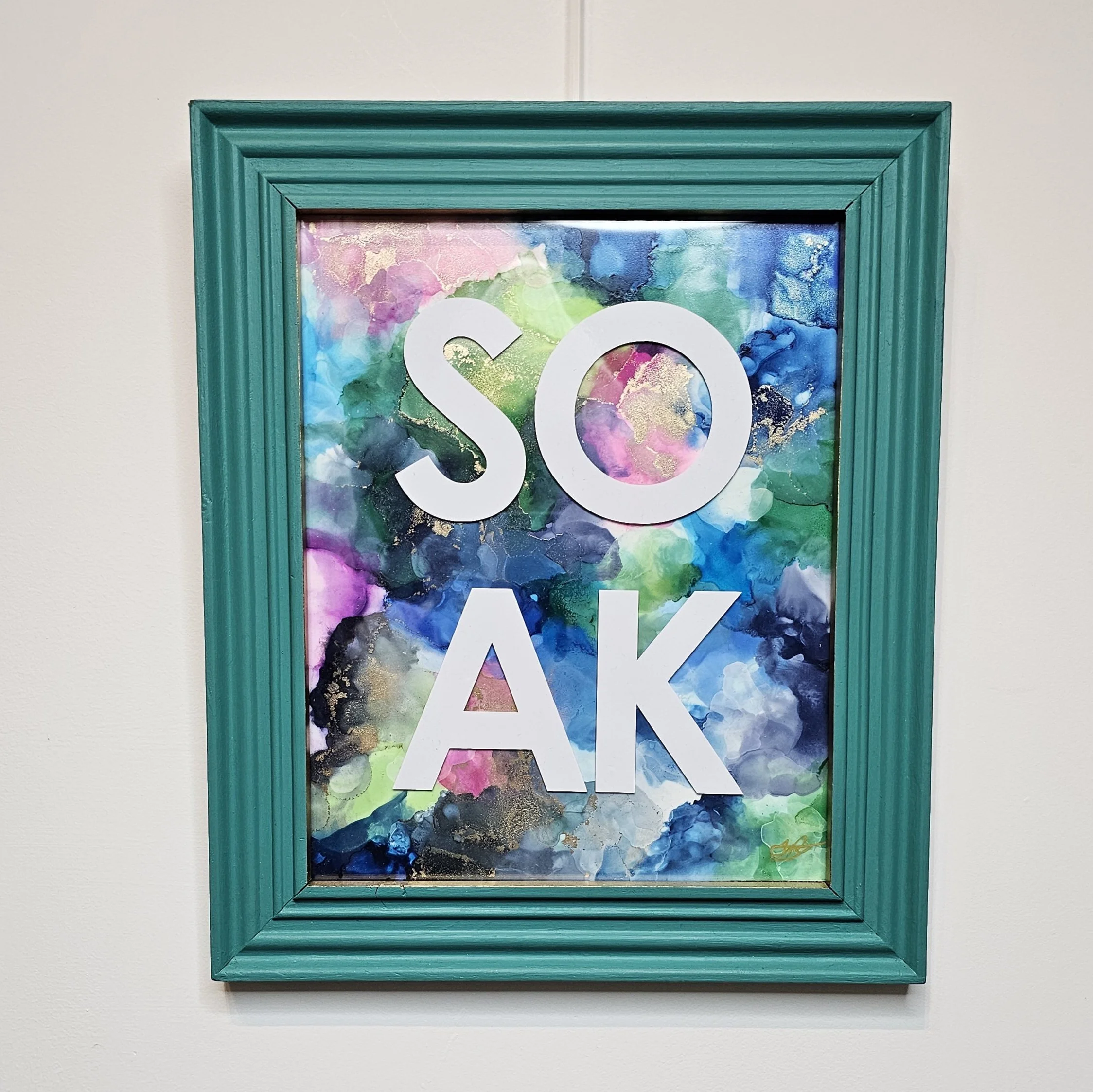 Original alcohol ink art for bathroom with blue and pink colors, upcycled mermaid green frame with the word SOAK.