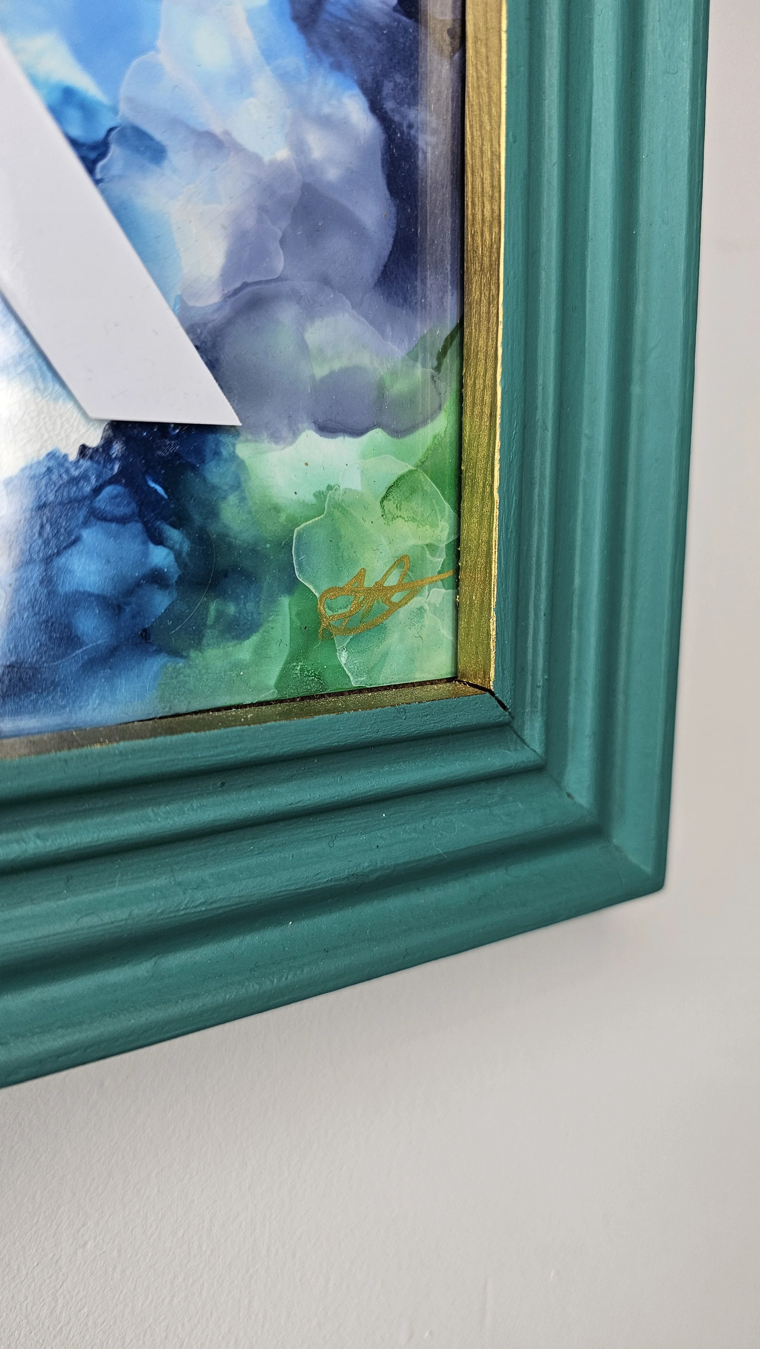 Close up of picture frame showing gold edge and gold signature on original alcohol ink art