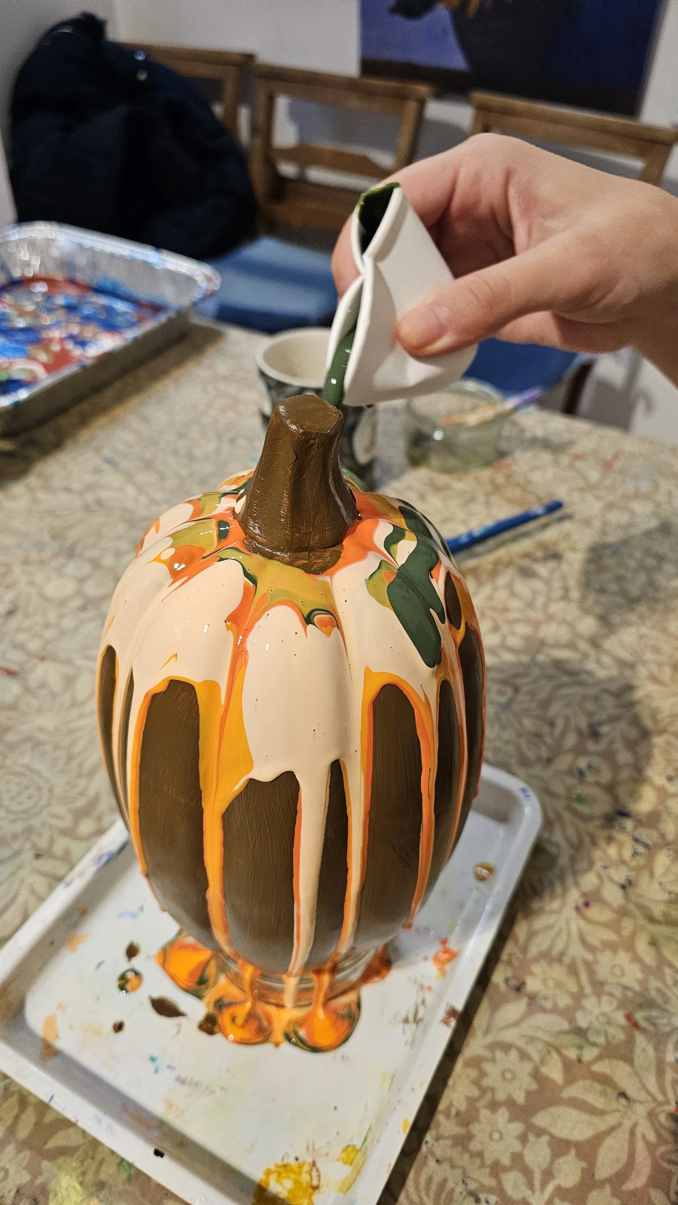 acrylic paint pouring onto a ceramic pumpkin
