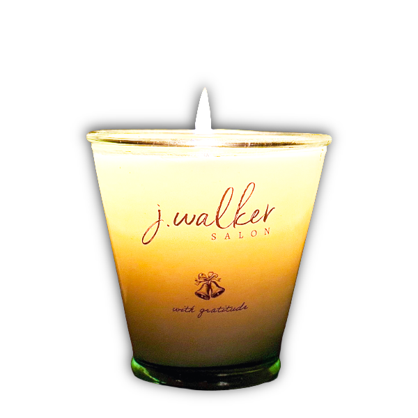 A lit candle in a glass container with the text 'j. walker SALON with gratitude' on it.