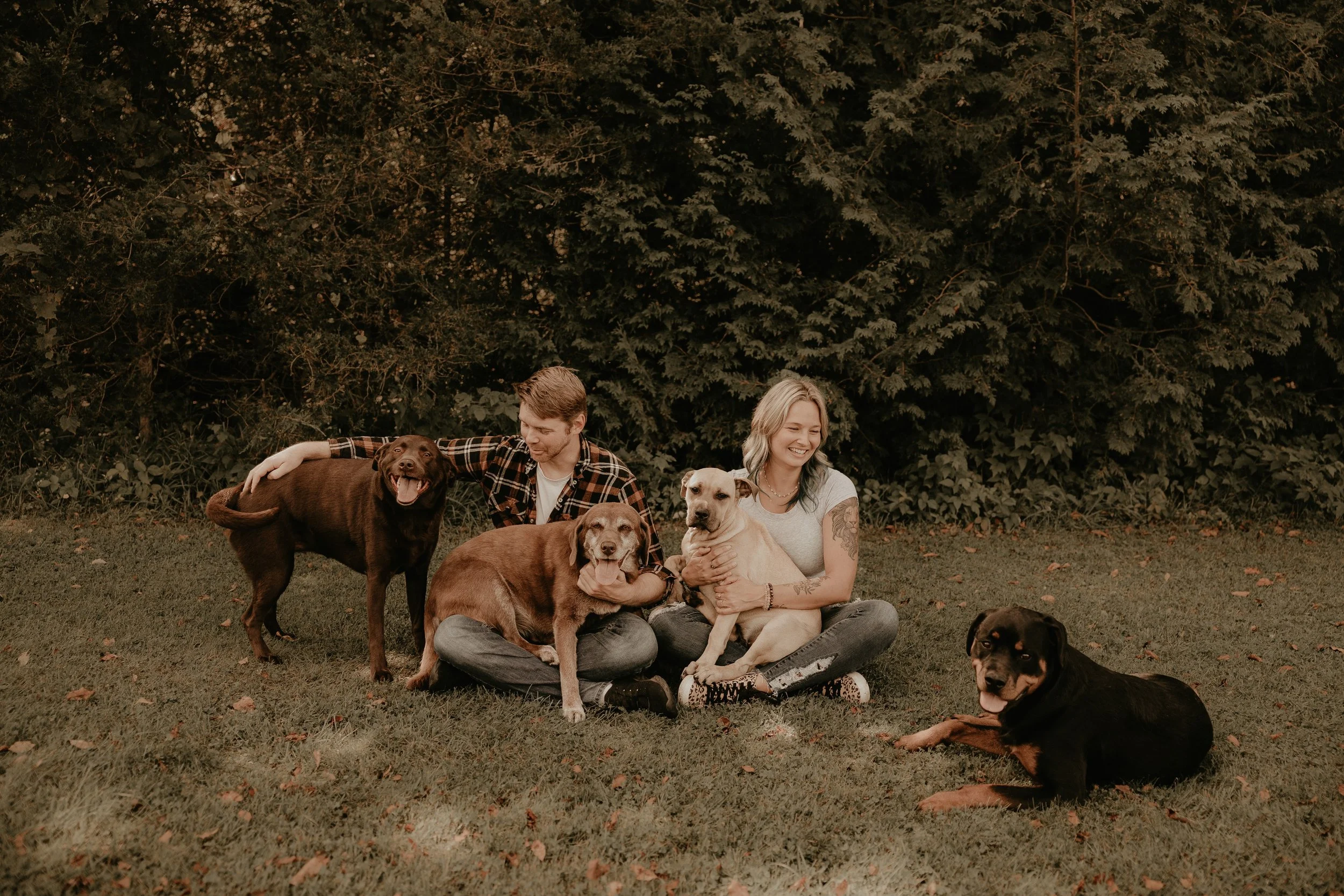 Coach Kate and Mr. SimplyStrong MBC sitting on grass with four dogs in front of trees.