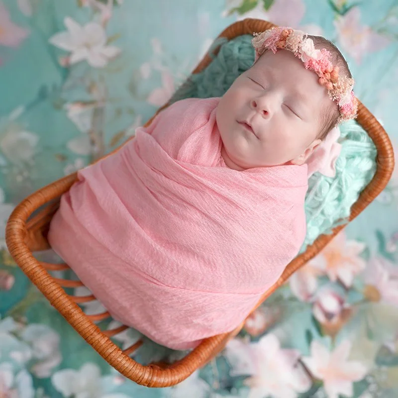 Kleines Baby in einem Korb eingewickelt in einem pinken Tuch.