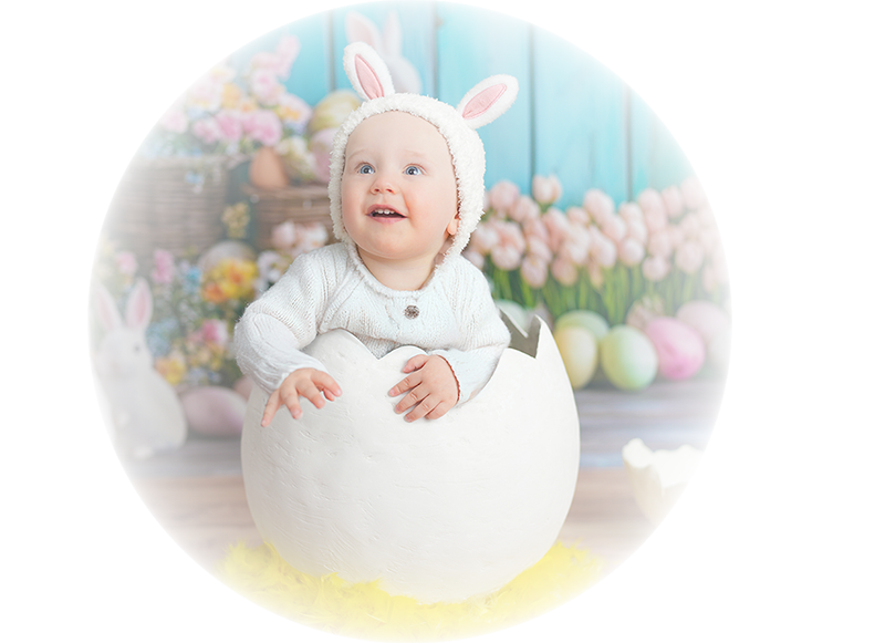 Ein Baby mit Hasenohren-Kopfbedeckung sitzt in einem großen, zerbrochenen Eierschale.