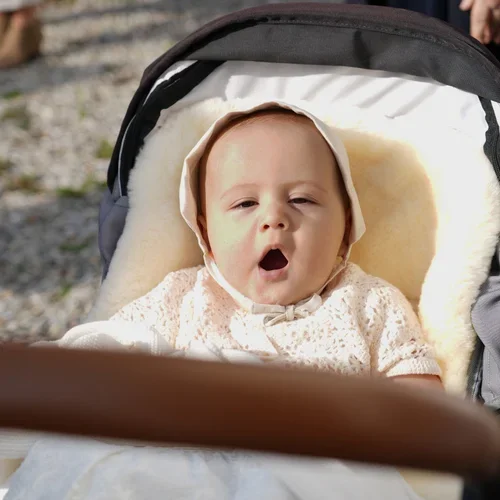 Baby liegt während der Taufe in einem Kinderwagen vor der Kirche.