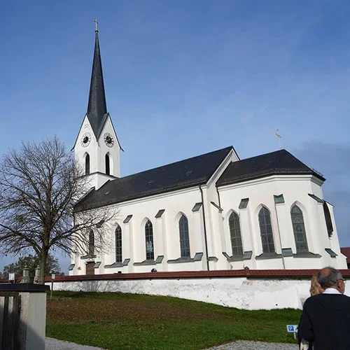 Weiße Kirche mit Kirchturm unter blauem Himmel am Tag der Taufe.