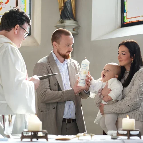 Eltern halten ihr Baby gemeinsam mit dem Pfarrer während der Taufe.