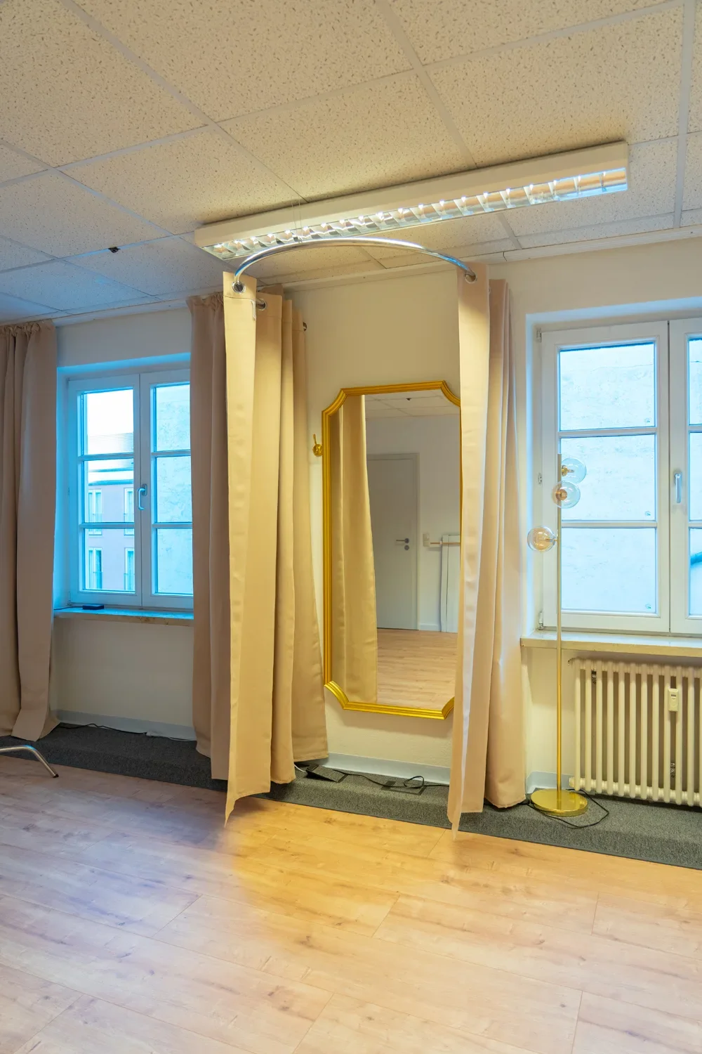 Heller Umkleidebereich mit Spiegel und Vorhängen im Fotostudio in Mühldorf.