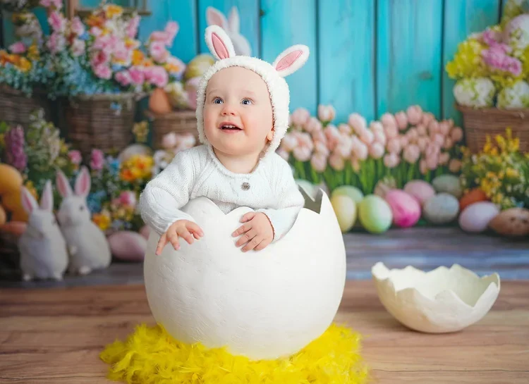 Lächelndes Baby sitzt in einer weißen Eierschale bei einem Oster-Fotoshooting.