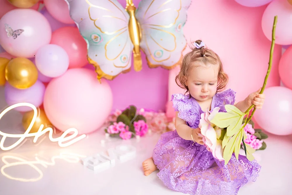 Lachendes Mädchen im lila Kleid bei einem farbenfrohen Cake Smash Shooting.