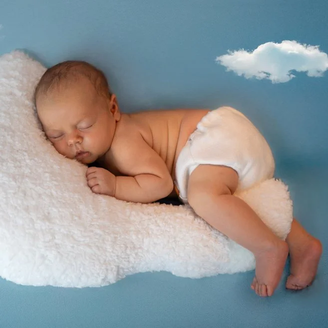Kleines Baby schläft auf einem weichen, weißen Kissen, mit Himmel und Wolke im Hintergrund.