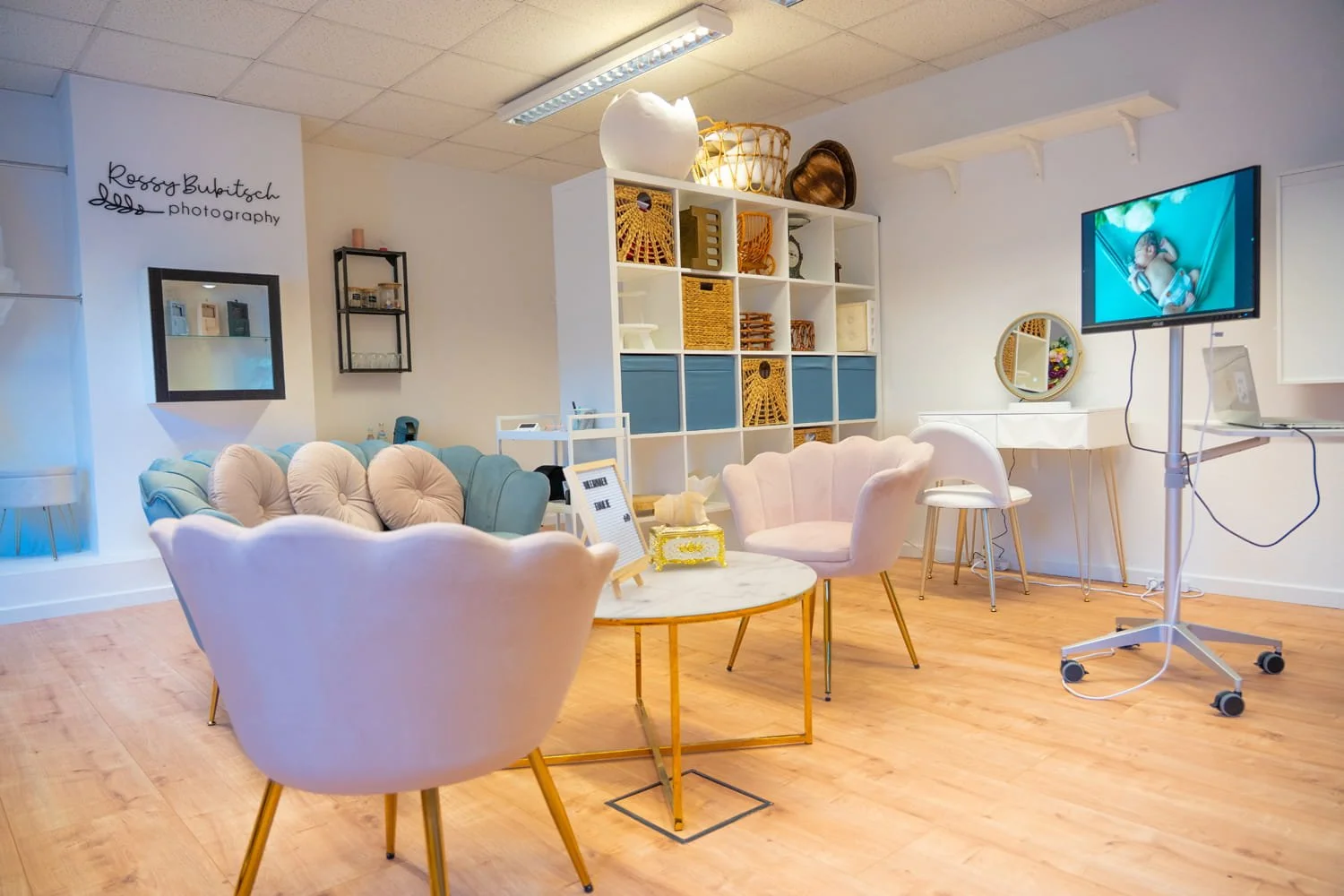 Ein gemütlicher Wartebereich mit Sofas, Stühlen, einem Bücherregal und Dekoration in hellen Farben.