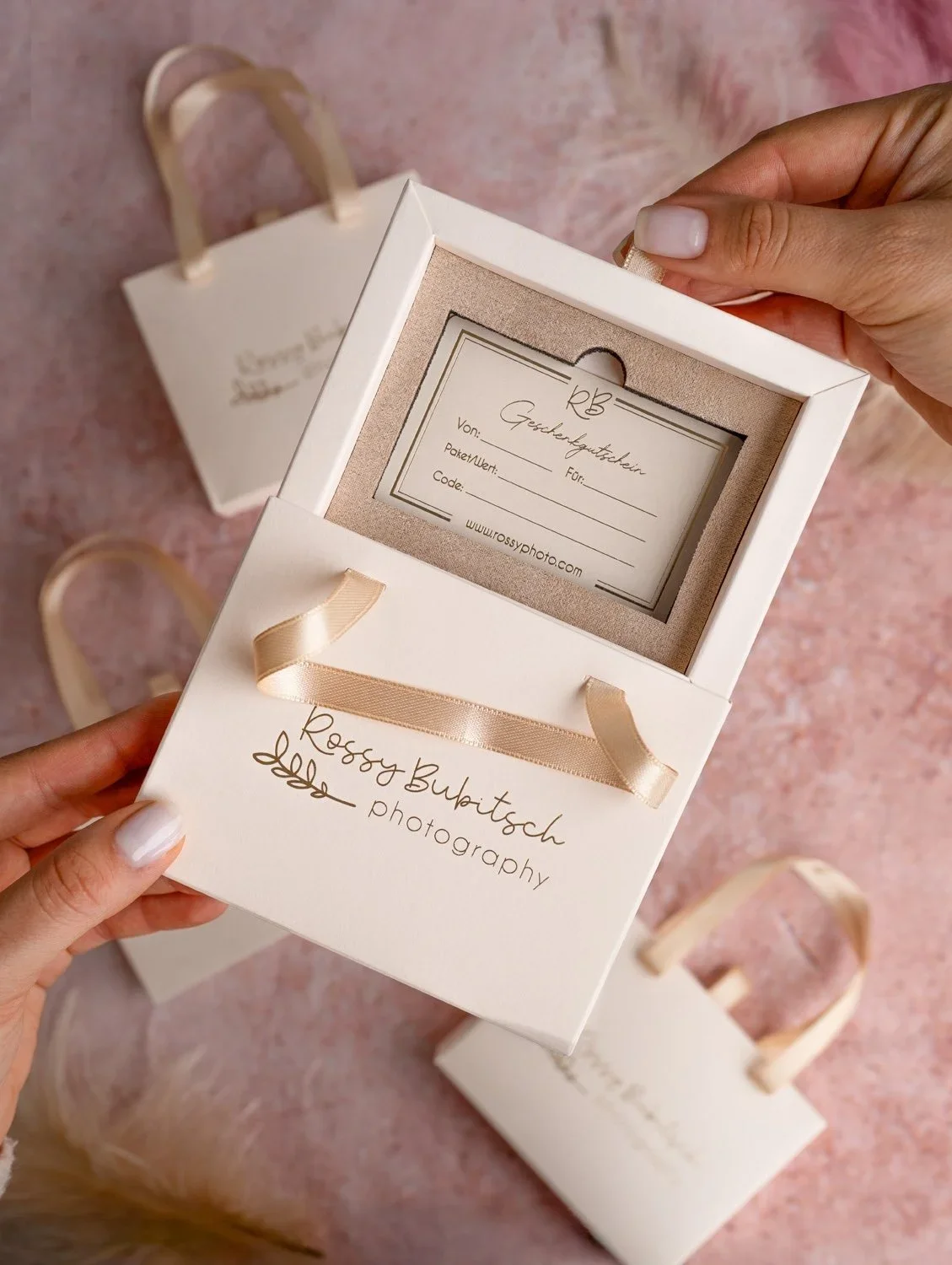Ein Geschenkgutschein mit einem Gutschein und einem kleinen weißen Geschenkbeutel auf rosa Oberfläche.