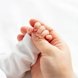 Kleine Babyhand hält während des Newborn Shootings behutsam einen Finger.