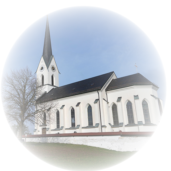 Weiße katholische Kirche mit spitzem Kirchturm und hohen Fenstern.
