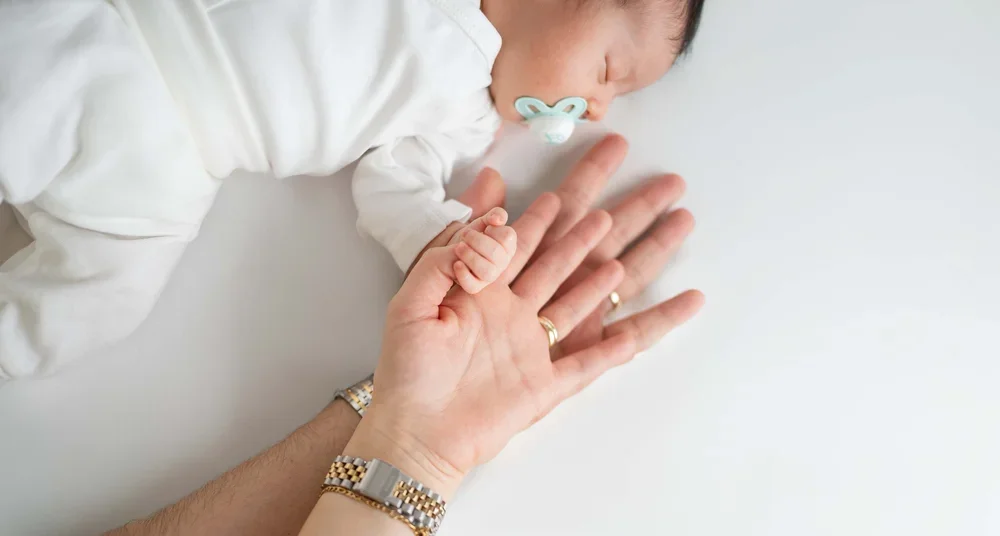 Baby hält beim Newborn Shooting mit seiner kleinen Hand einen Finger.