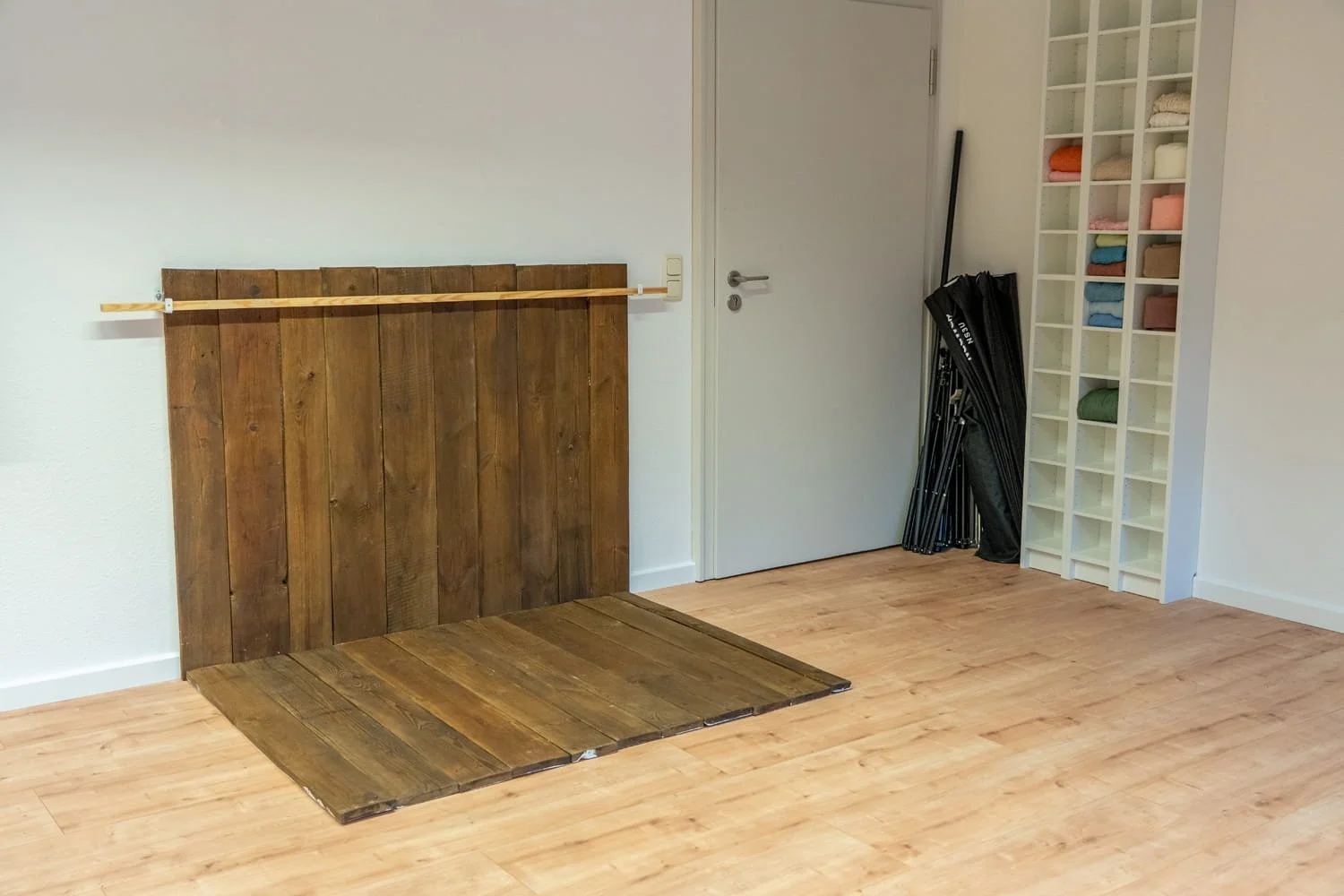 Ein Fotostudio mit weißen Wänden und einem Holzpodest.