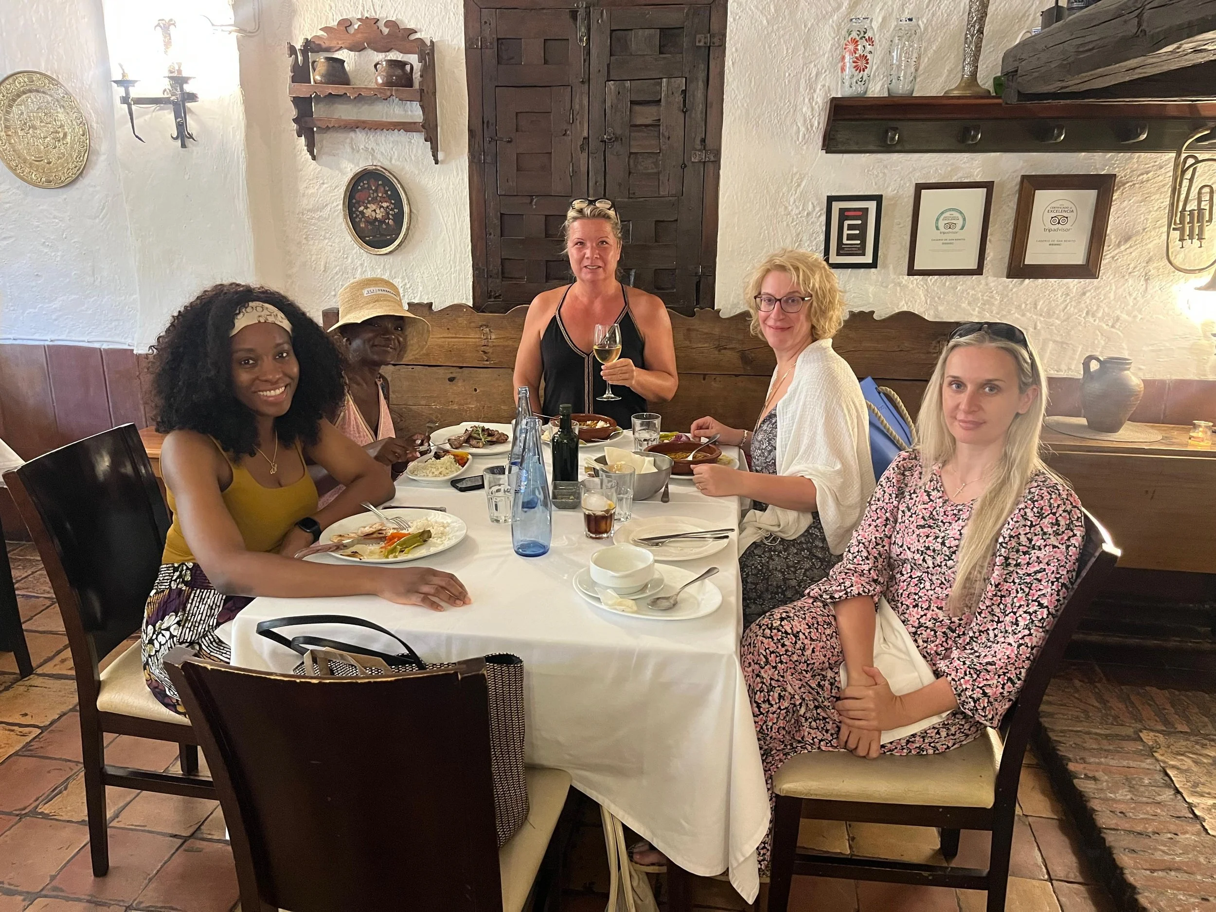 Group of people sitting around a campfire in a forest at night, surrounded by trees and illuminated by the firelight.