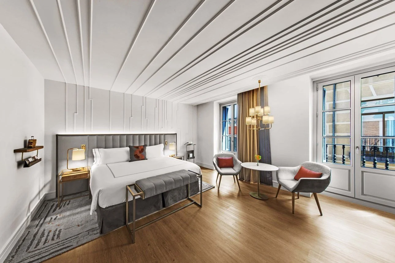 Camera da letto moderna con letto matrimoniale, sedie vicino alla finestra e decorazioni eleganti.