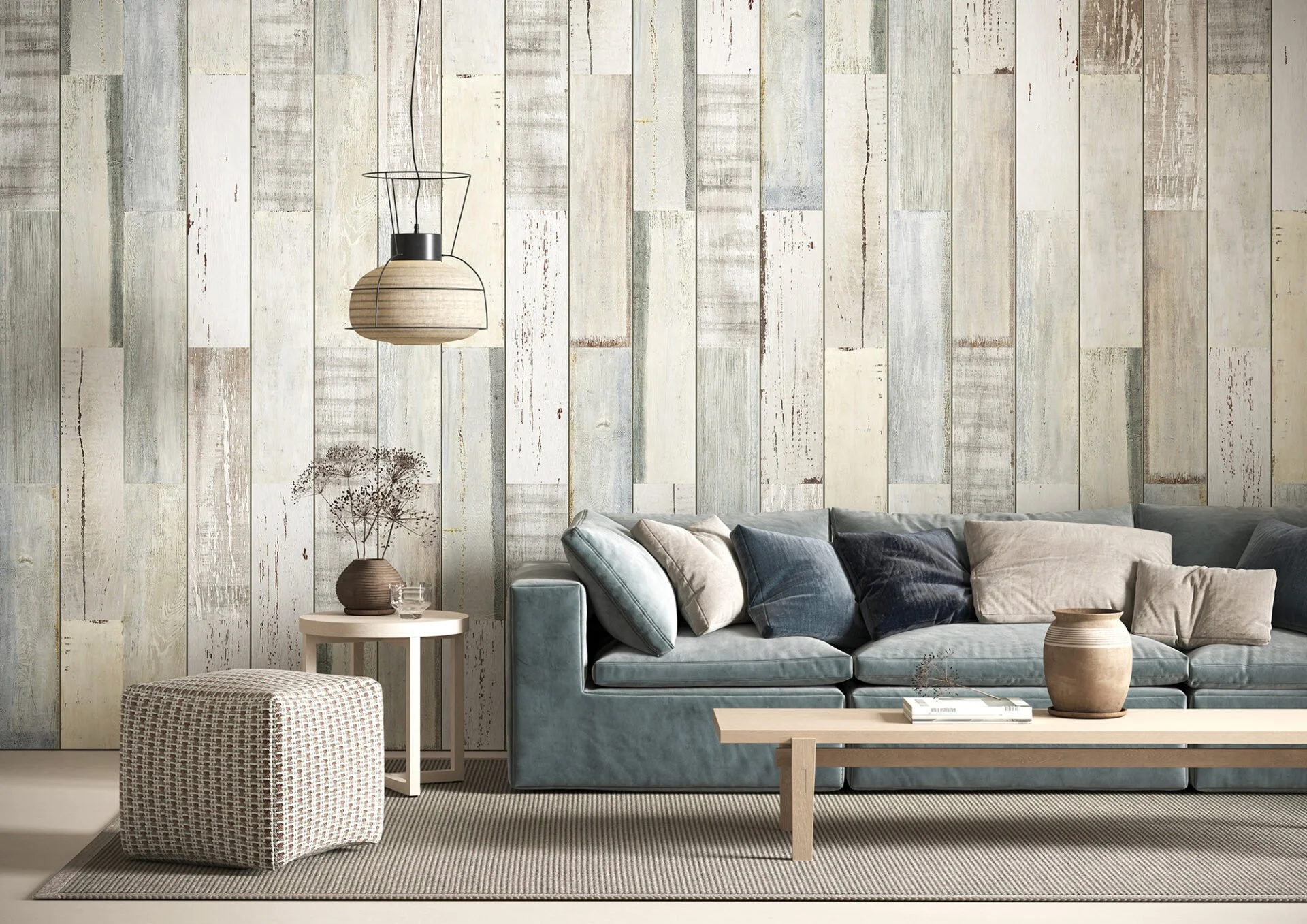 Soggiorno con divano grigio, tavolino in legno, pouf tessile, pareti in pannelli di legno chiaro, lampada sospesa in stile naturale, vasi con piante e libri.