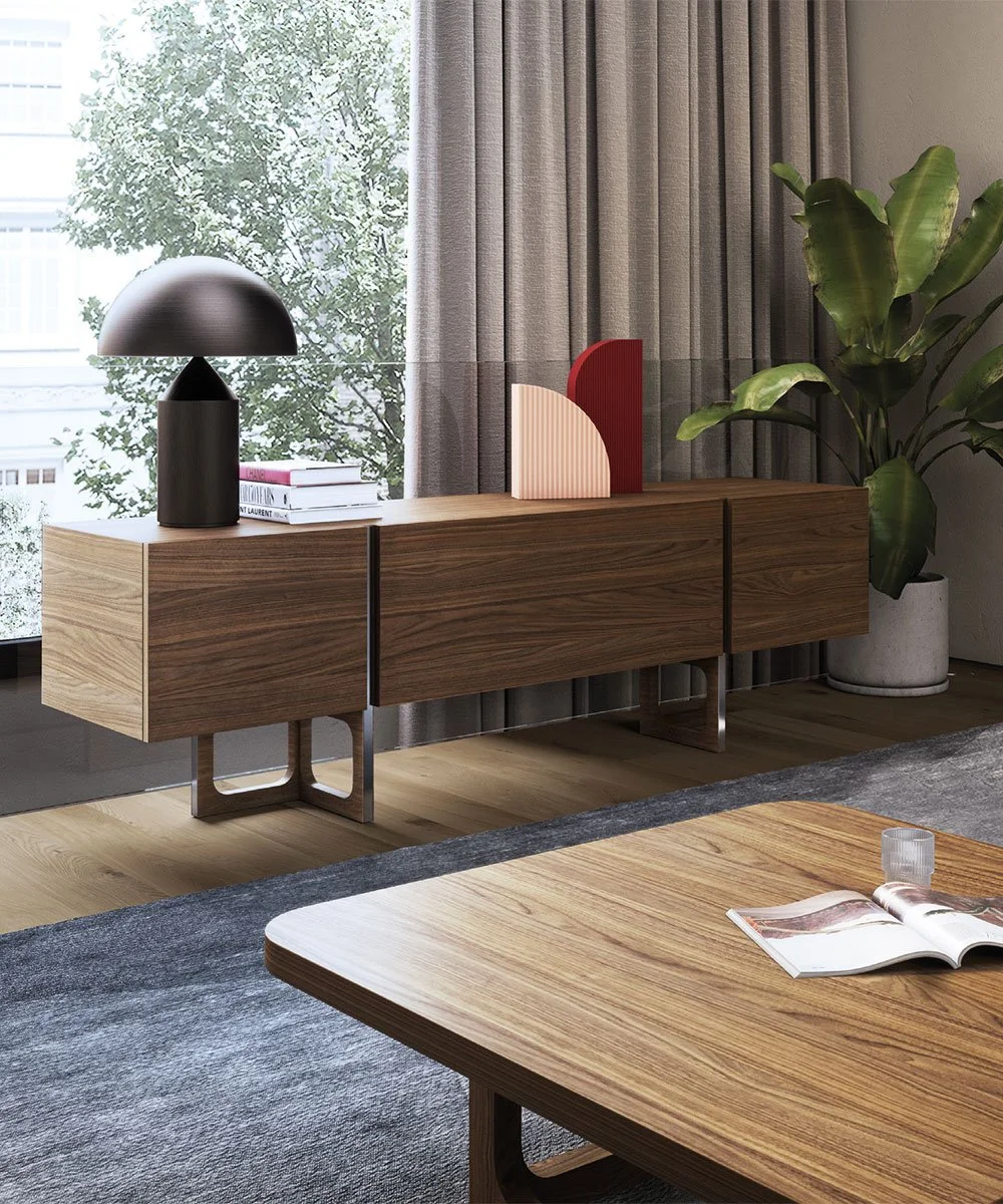 Una credenza in legno con un'illuminazione nera a forma di lampada e alcune decorazioni in plastica, con una grande pianta verde in secondo piano e una finestra con tende di fronte a un albero.
