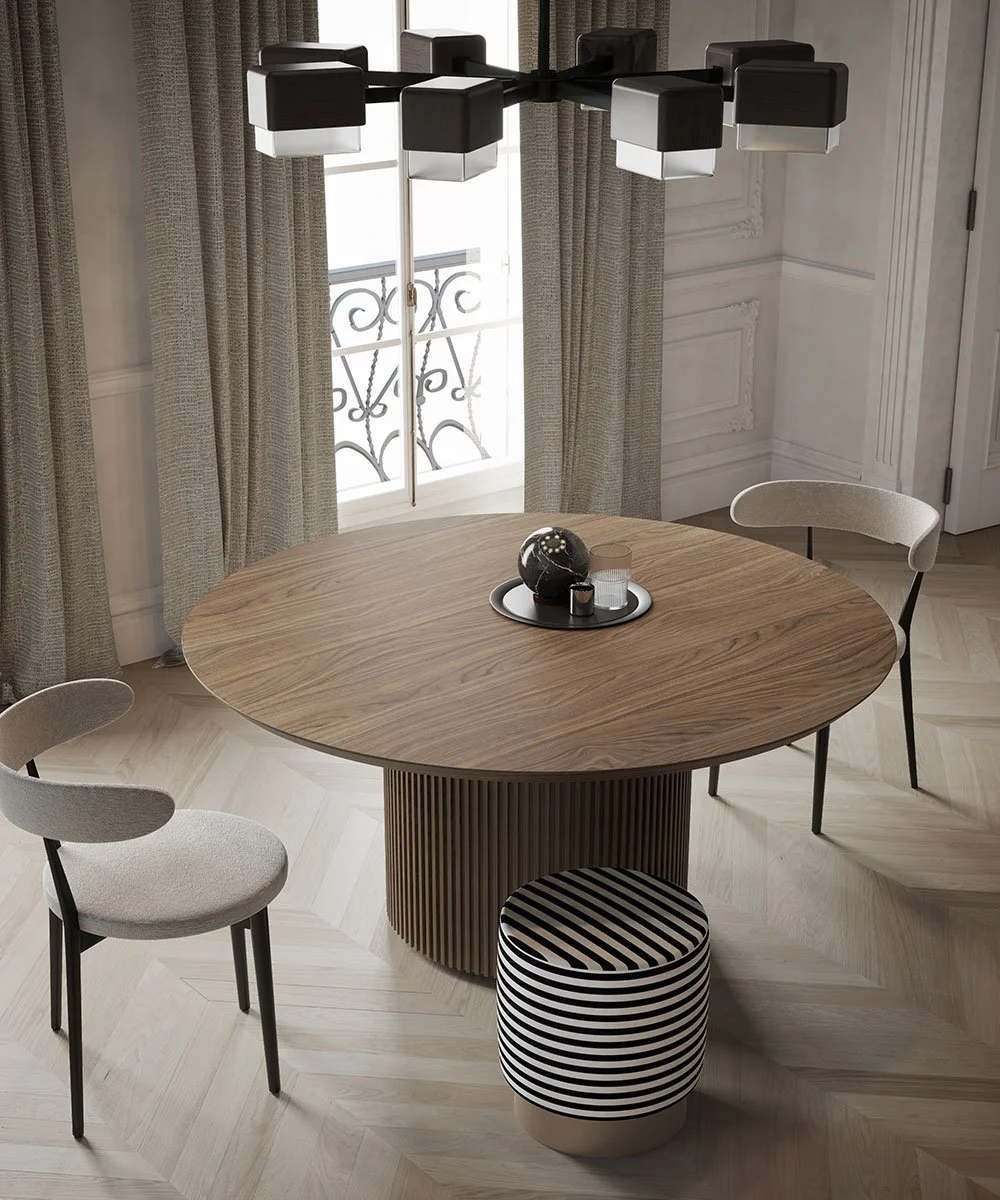 Sala da pranzo con tavolo rotondo in legno e sedie beige, lampadario moderno sopra, finestra con tende e sedia a pouf con motivo a righe nere e bianche.