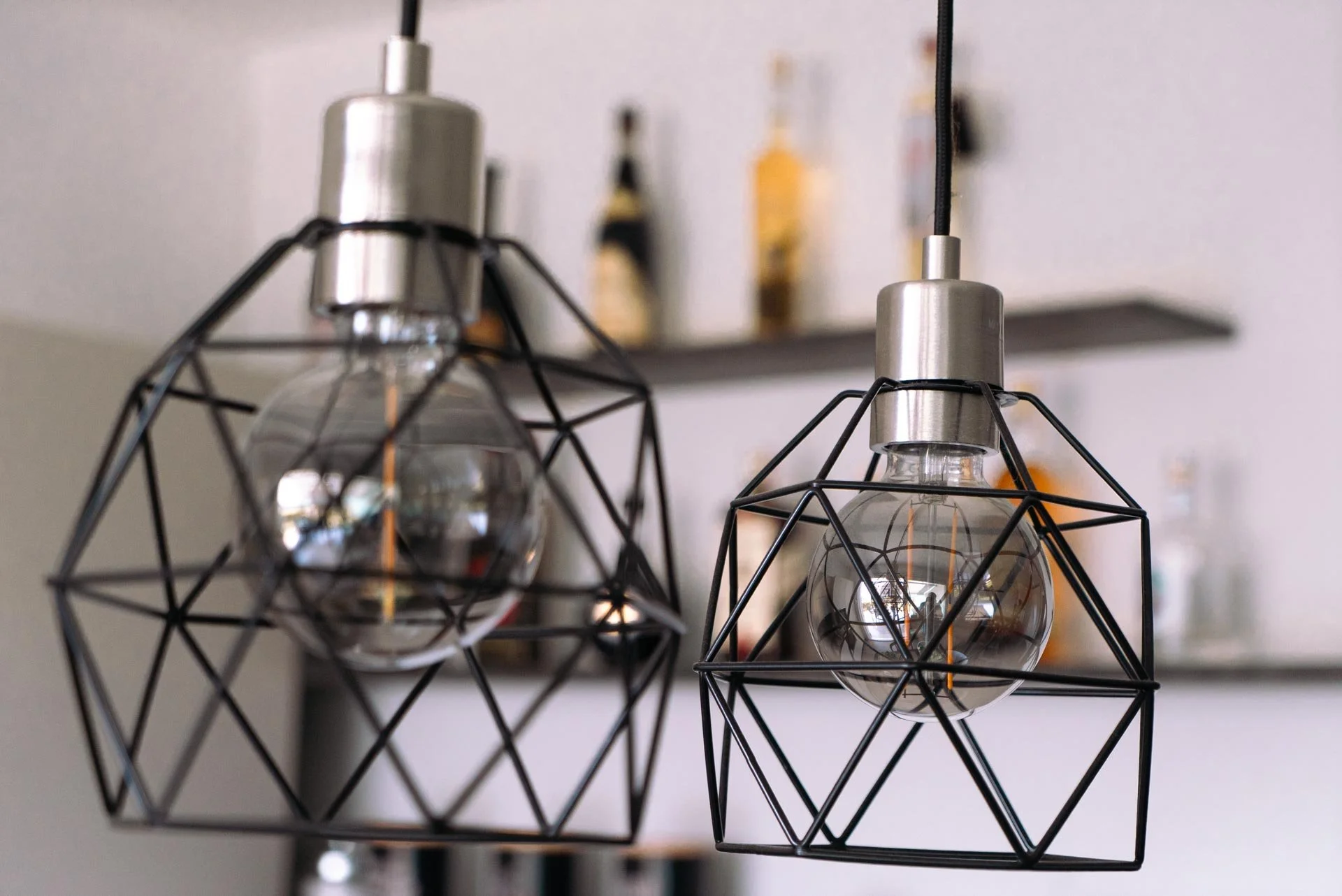Due lampade sospese con lampadine a vista e contenitori in metallo in stile industriale.
