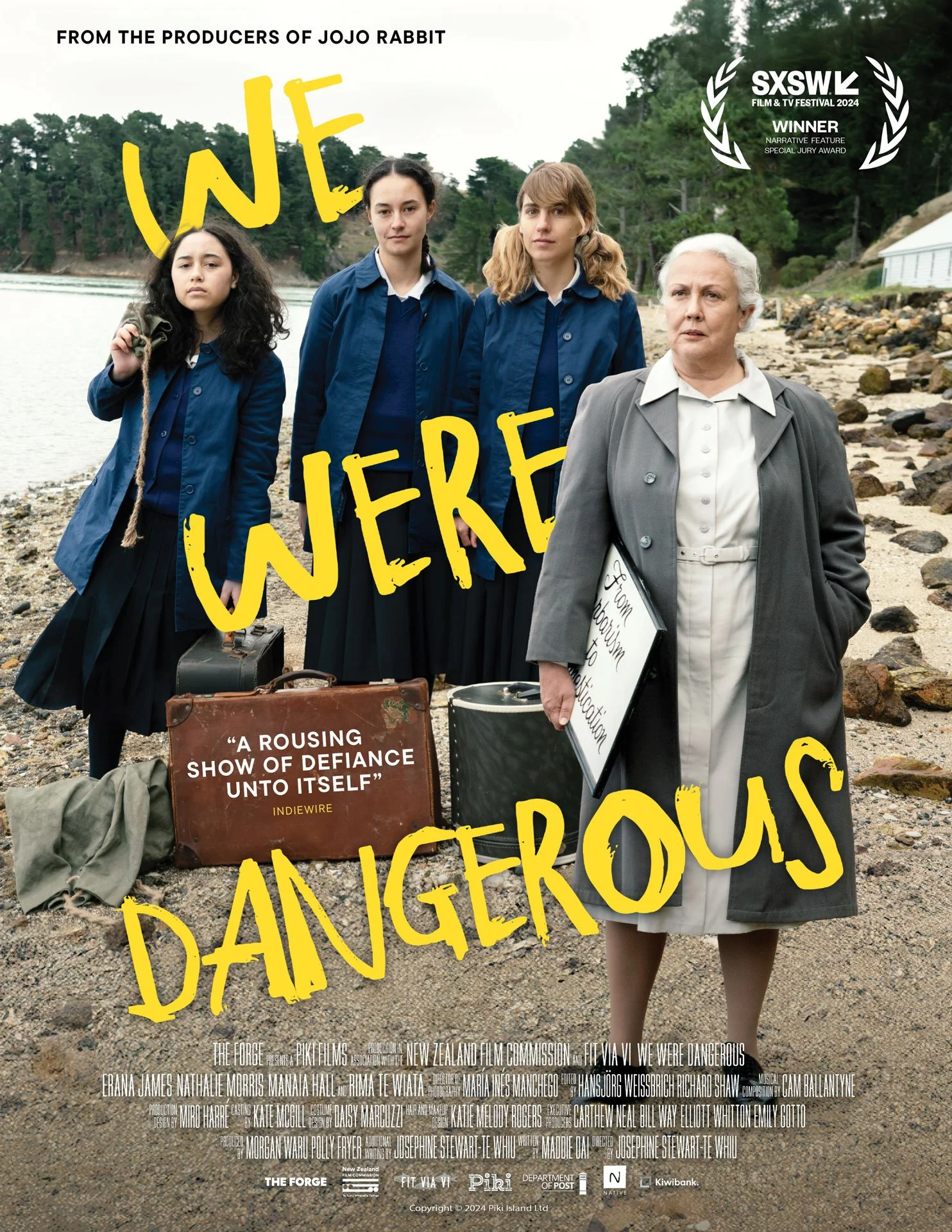 Movie poster for 'We Were Dangerous' featuring four women standing on a rocky shoreline. Three are in blue jackets, and one in white. Festival and producer credits are displayed at the top, with title in bold yellow letters.