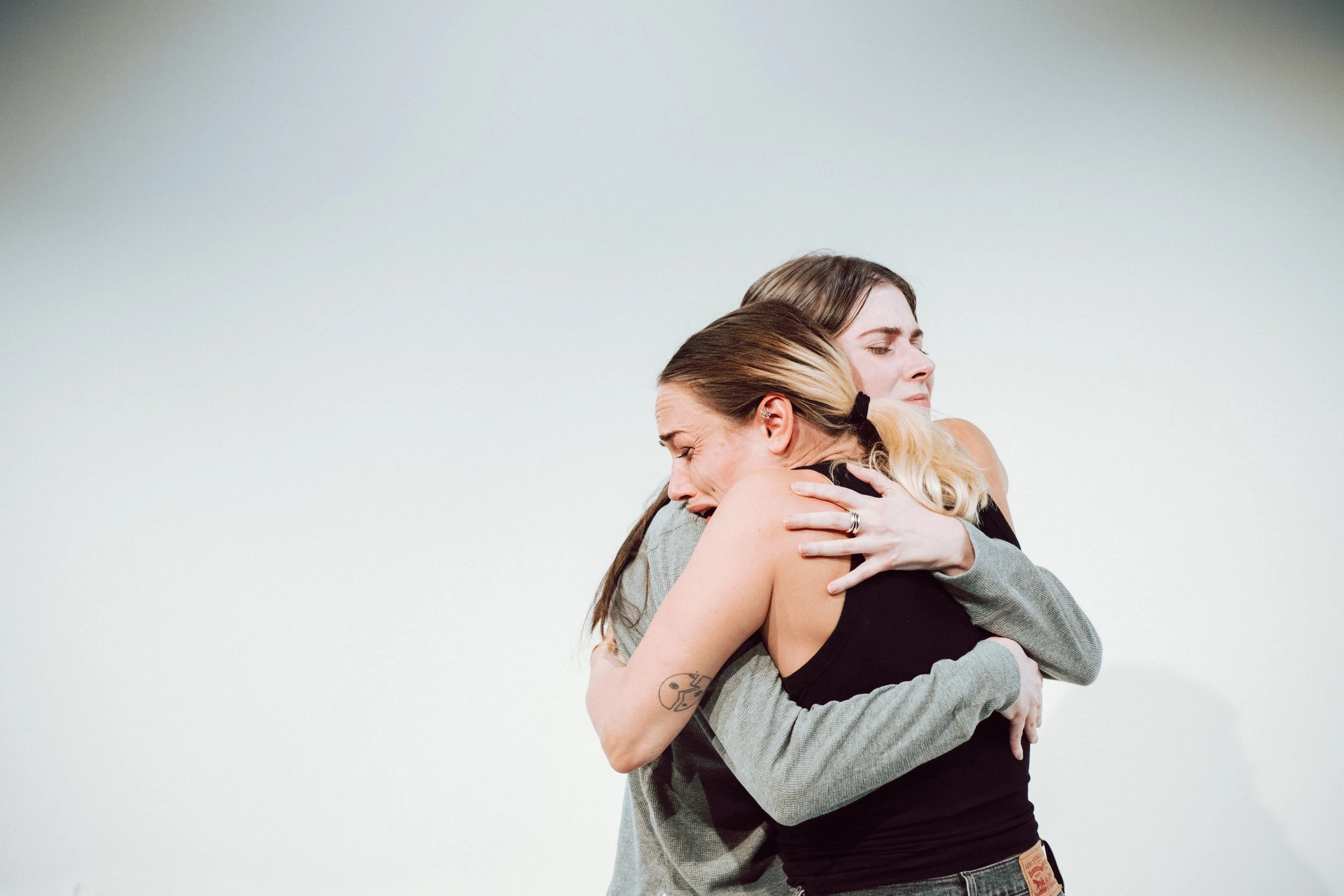 Two women hugging each other tightly with joyful expressions.