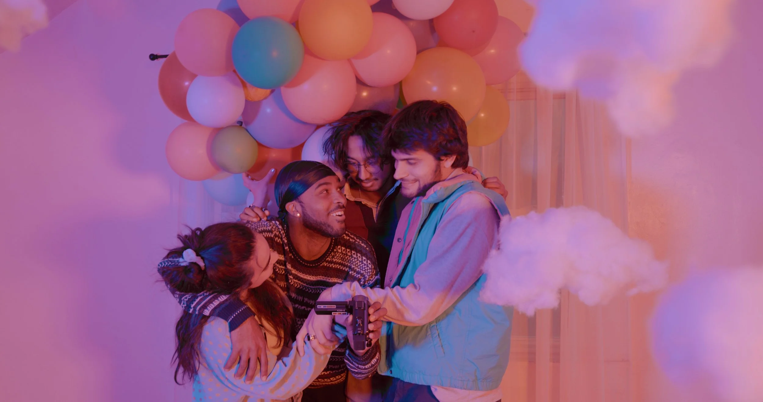 Group of diverse friends gathered together, smiling, with balloons and cotton candy, celebrating at a party.