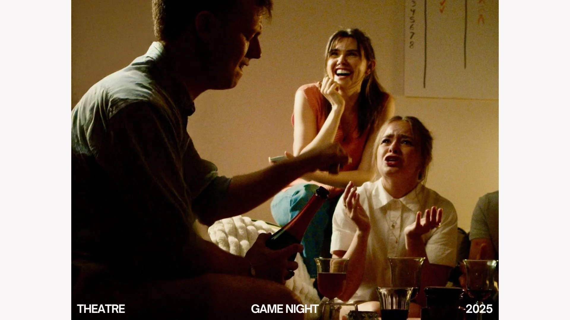 People enjoying a game night, with one person holding a bottle and others reacting humorously, in a warm, dimly lit room.