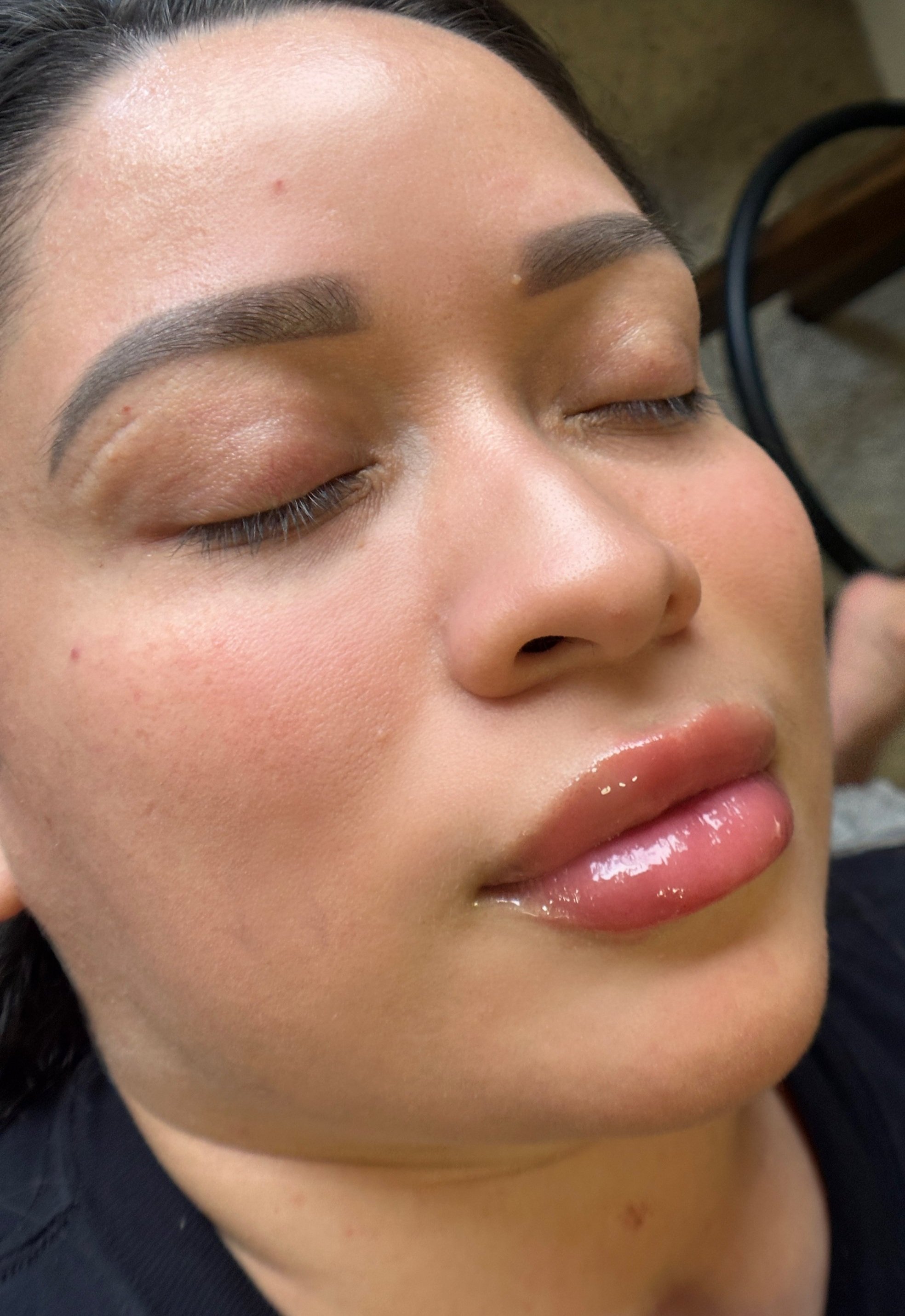 Close-up of a woman's face with closed eyes, and full lips.