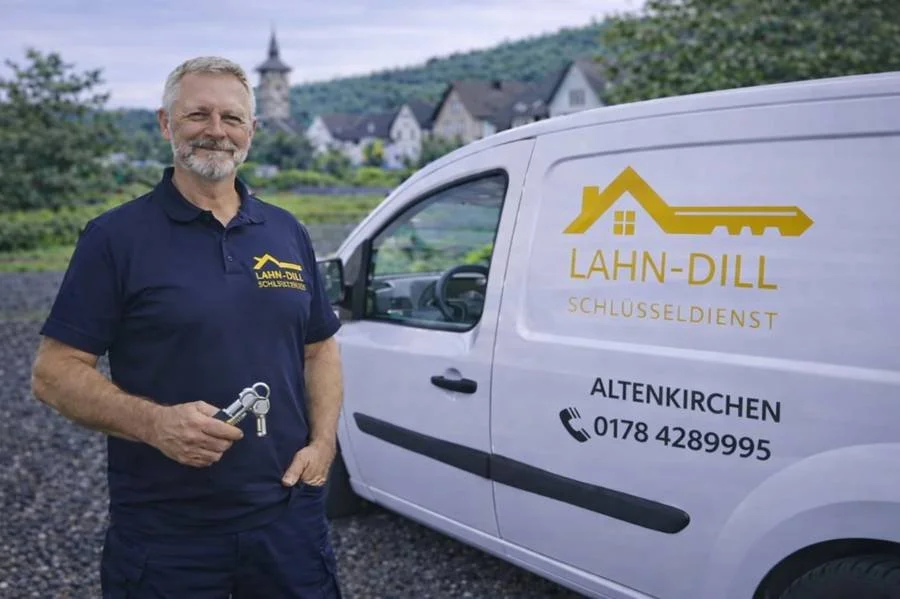Schlüsseldienst Monteur in Altenkirchen mit Servicefahrzeug und Schlüssel in der Hand